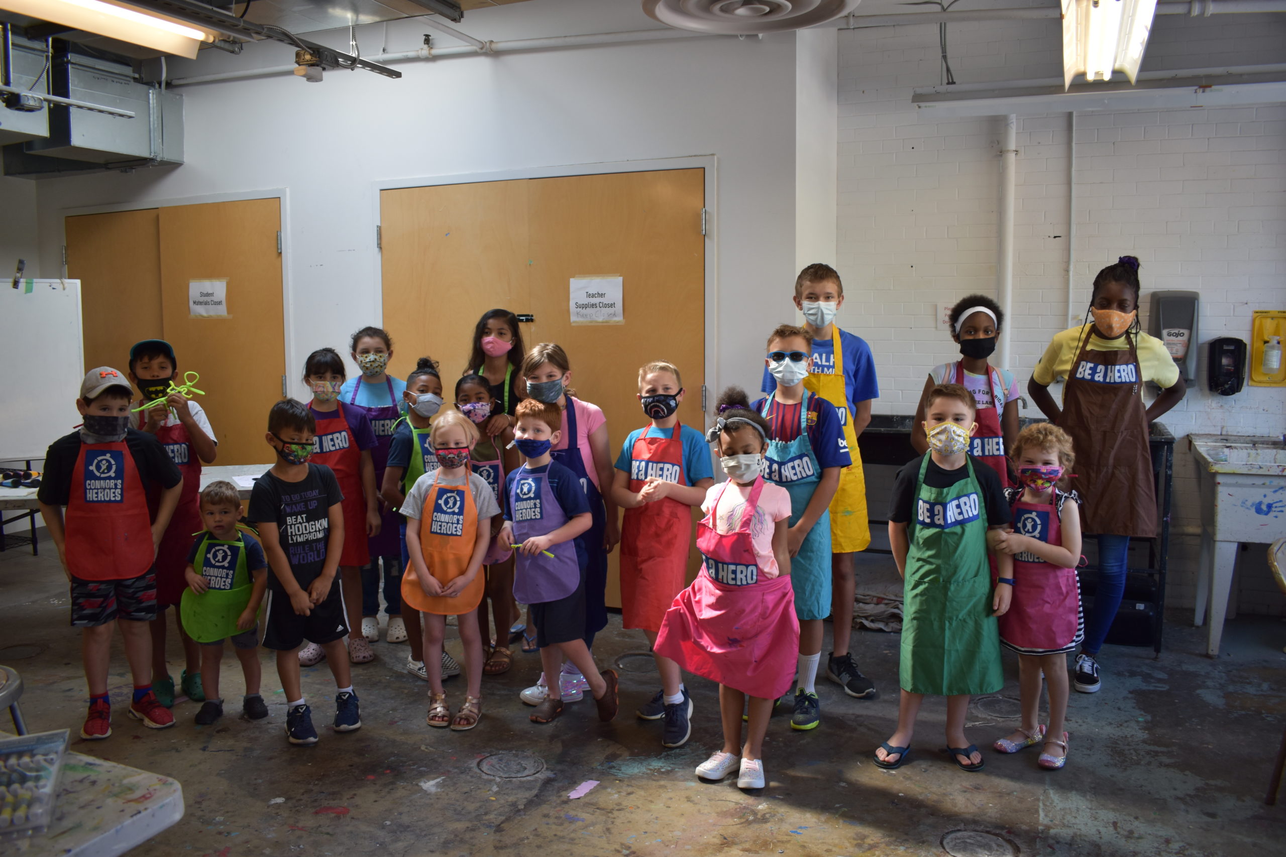 Image a group of 20 children stand together in an art studio