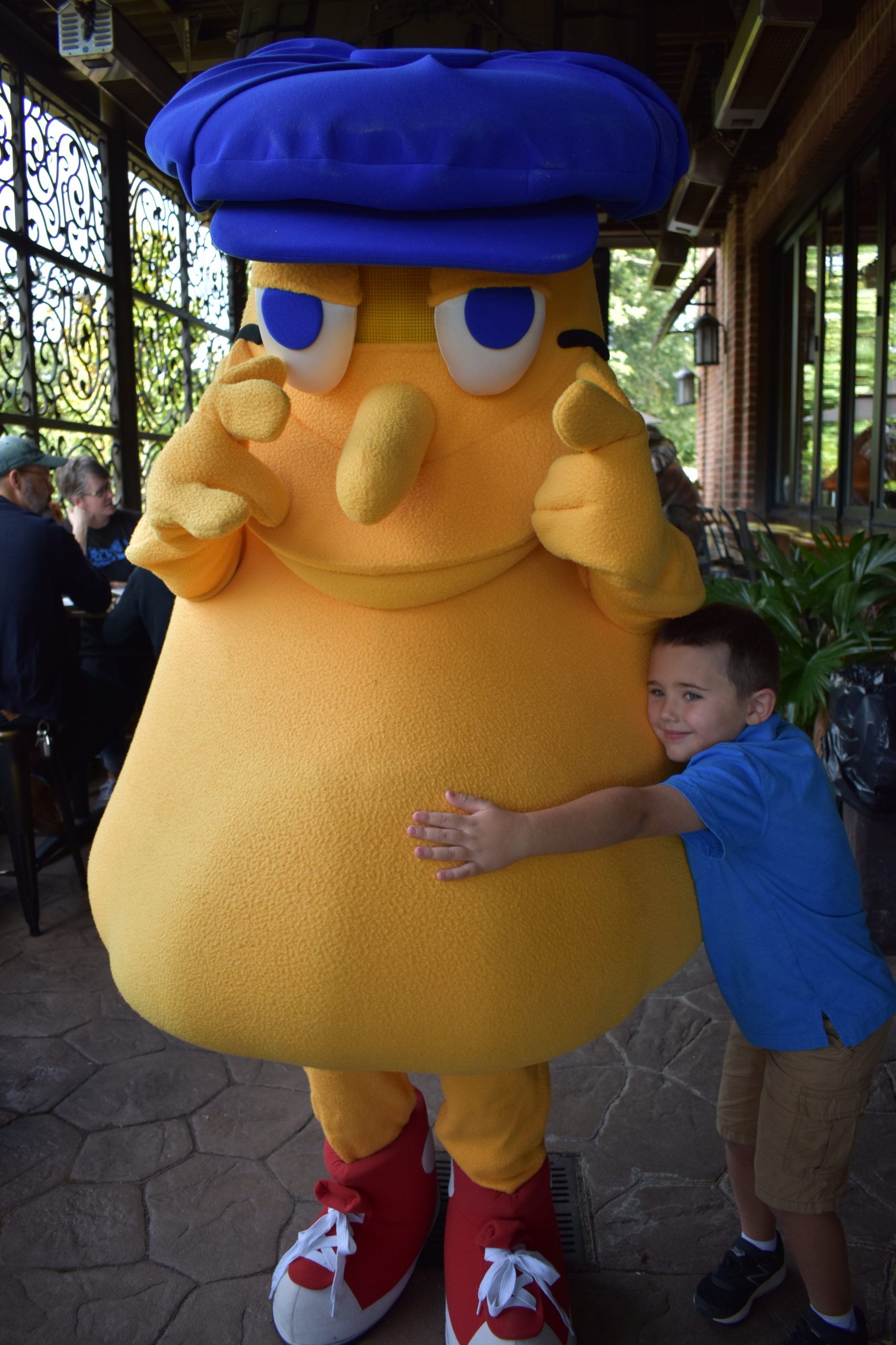 Image a child hugging a person wearing a yellow mushroom costume