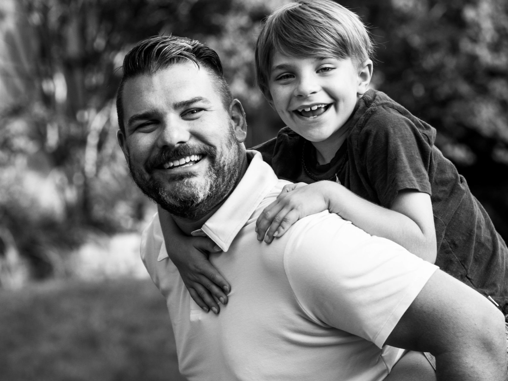Image a parent with a child riding on his back and both are laughing