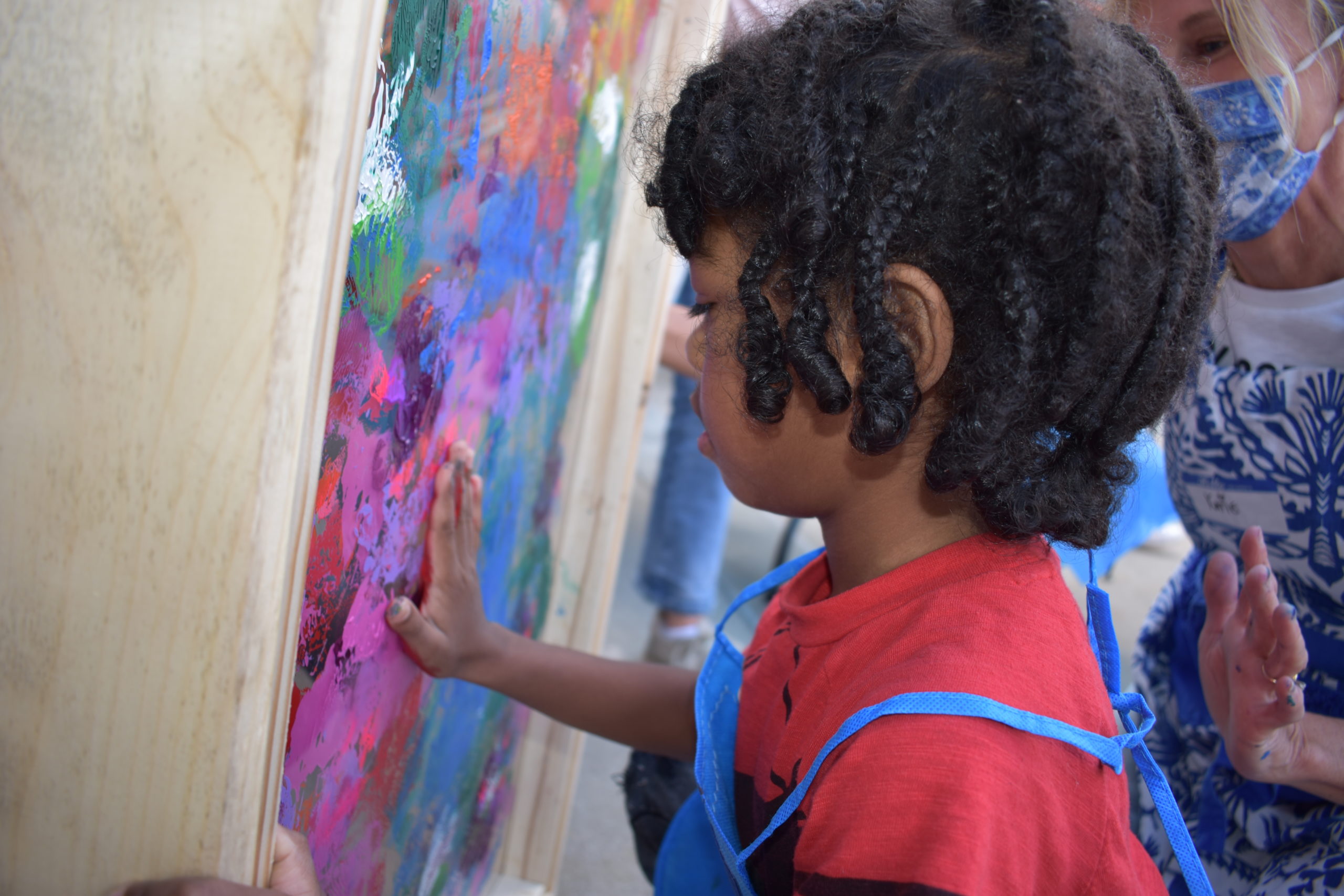 A child spreading paint with his hands