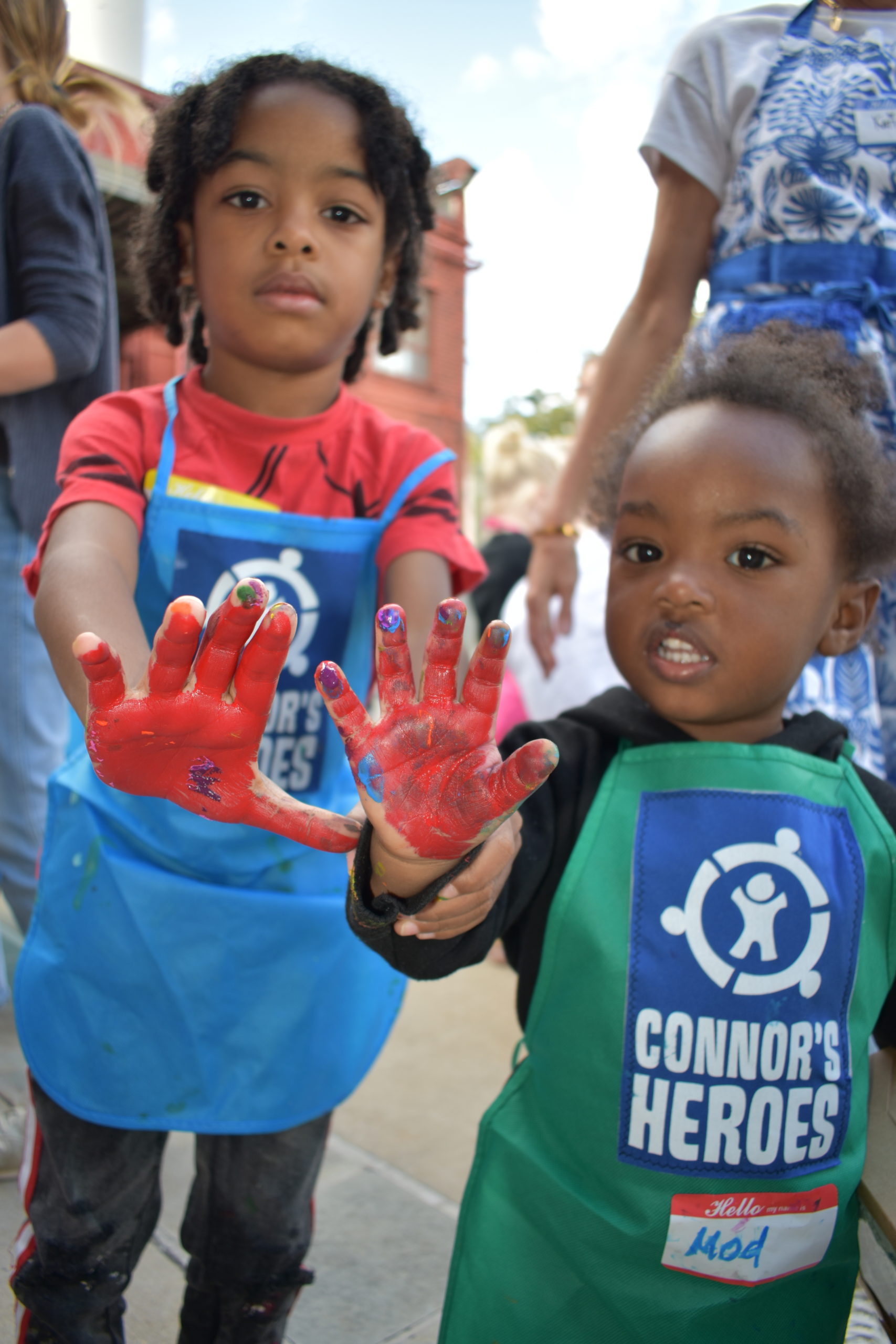 Two children holding up their hands that are covered with painted