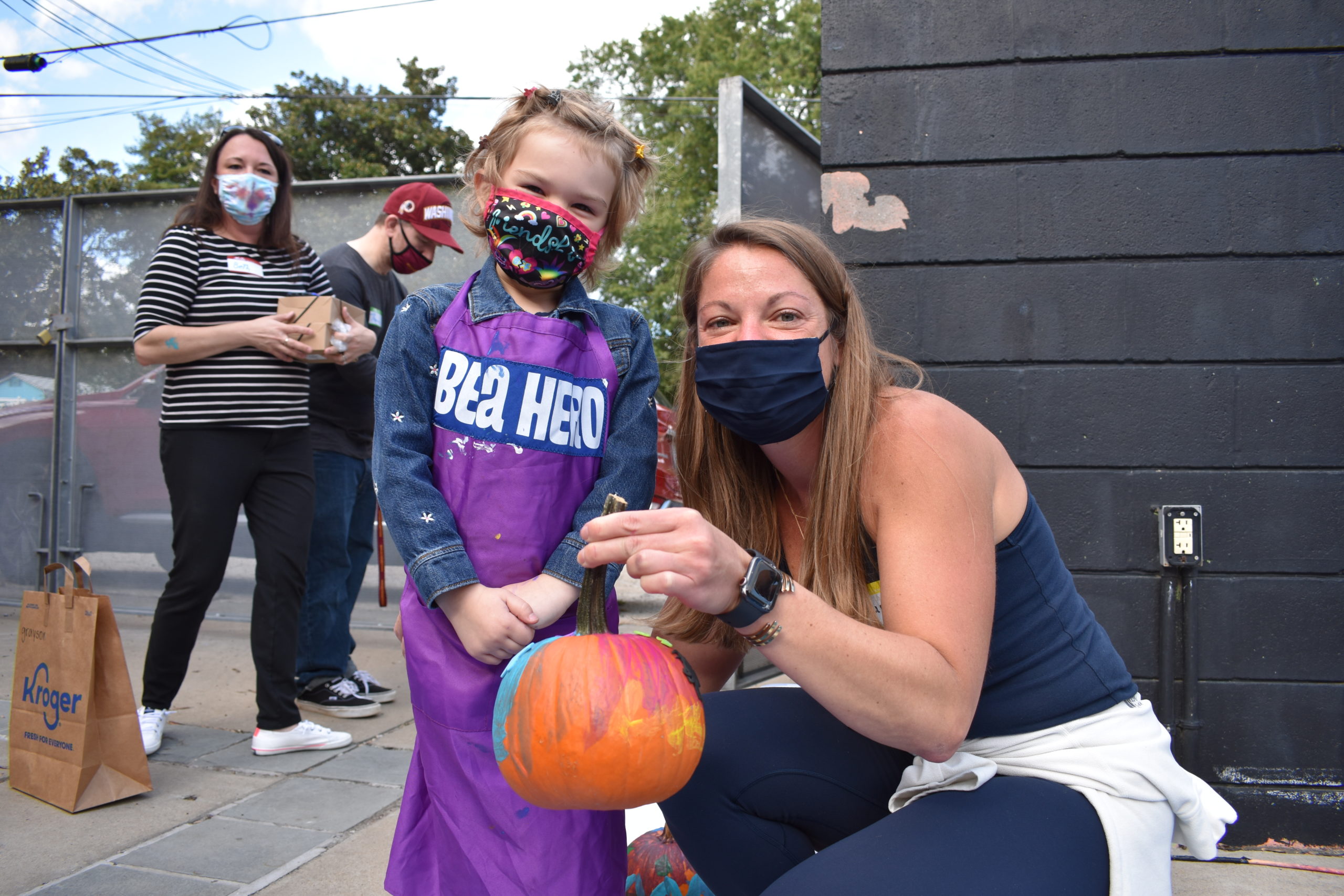 A child standing with an adult who is holding a pumpkin