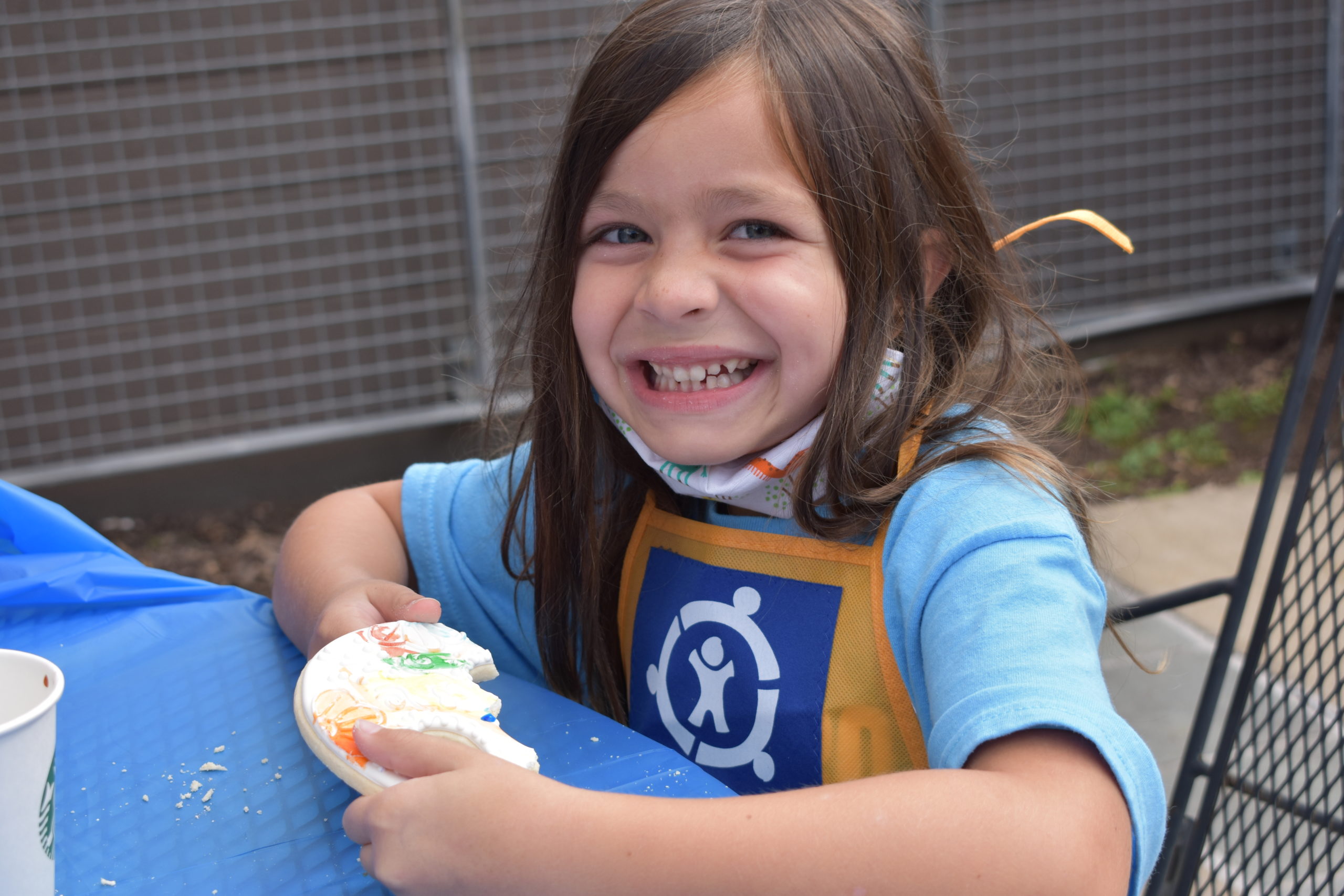 A child smiling and holding a cookie