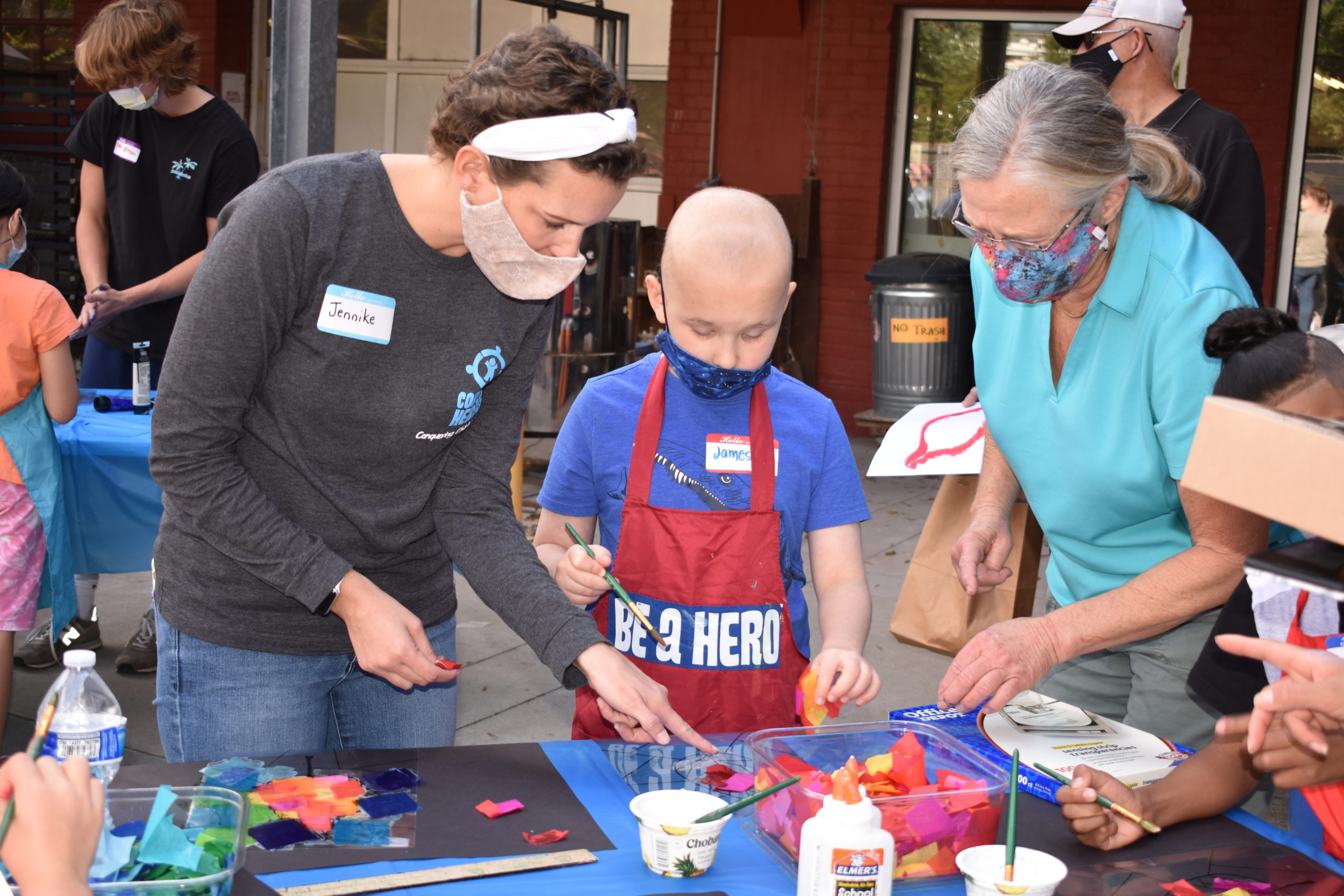 Two adults helping a child work on a craft