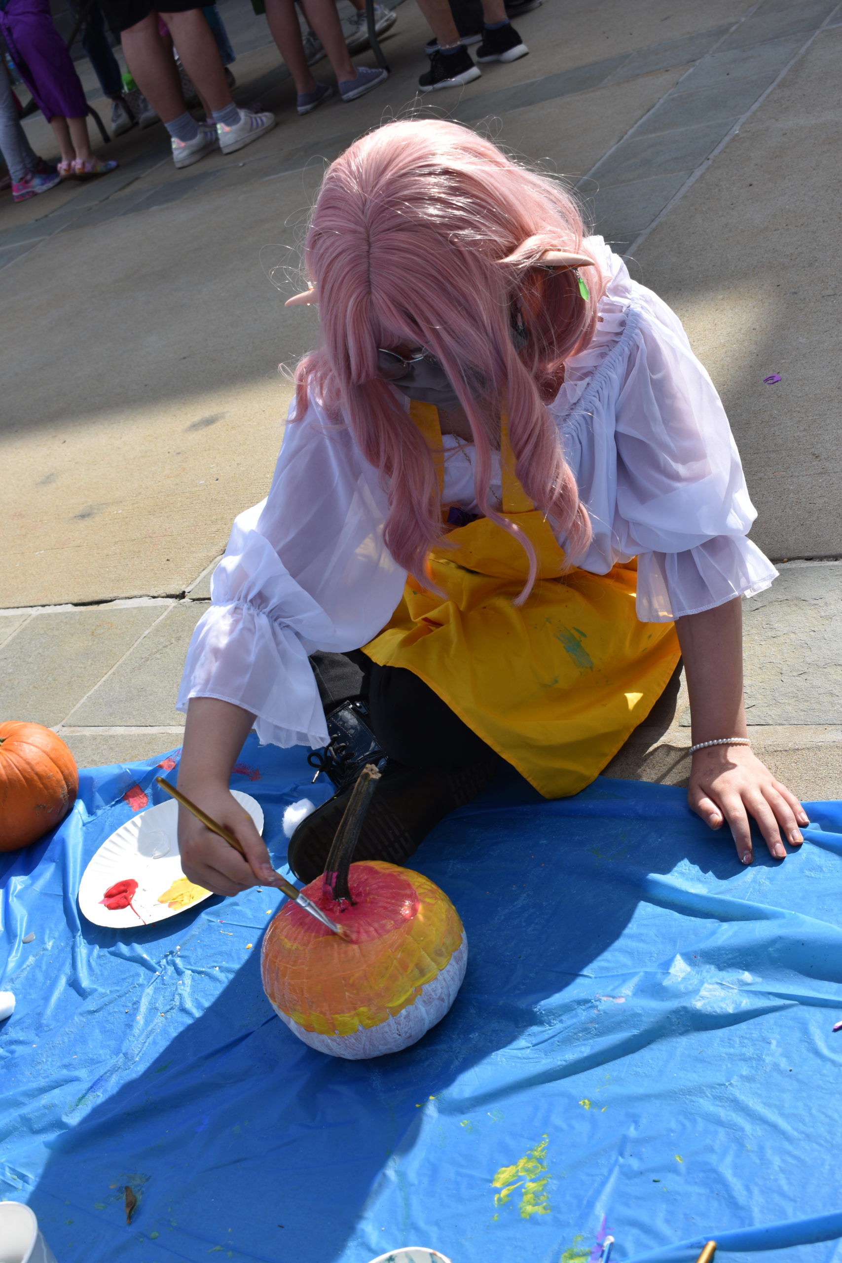 Child is outside decorating a pumpkin with paint