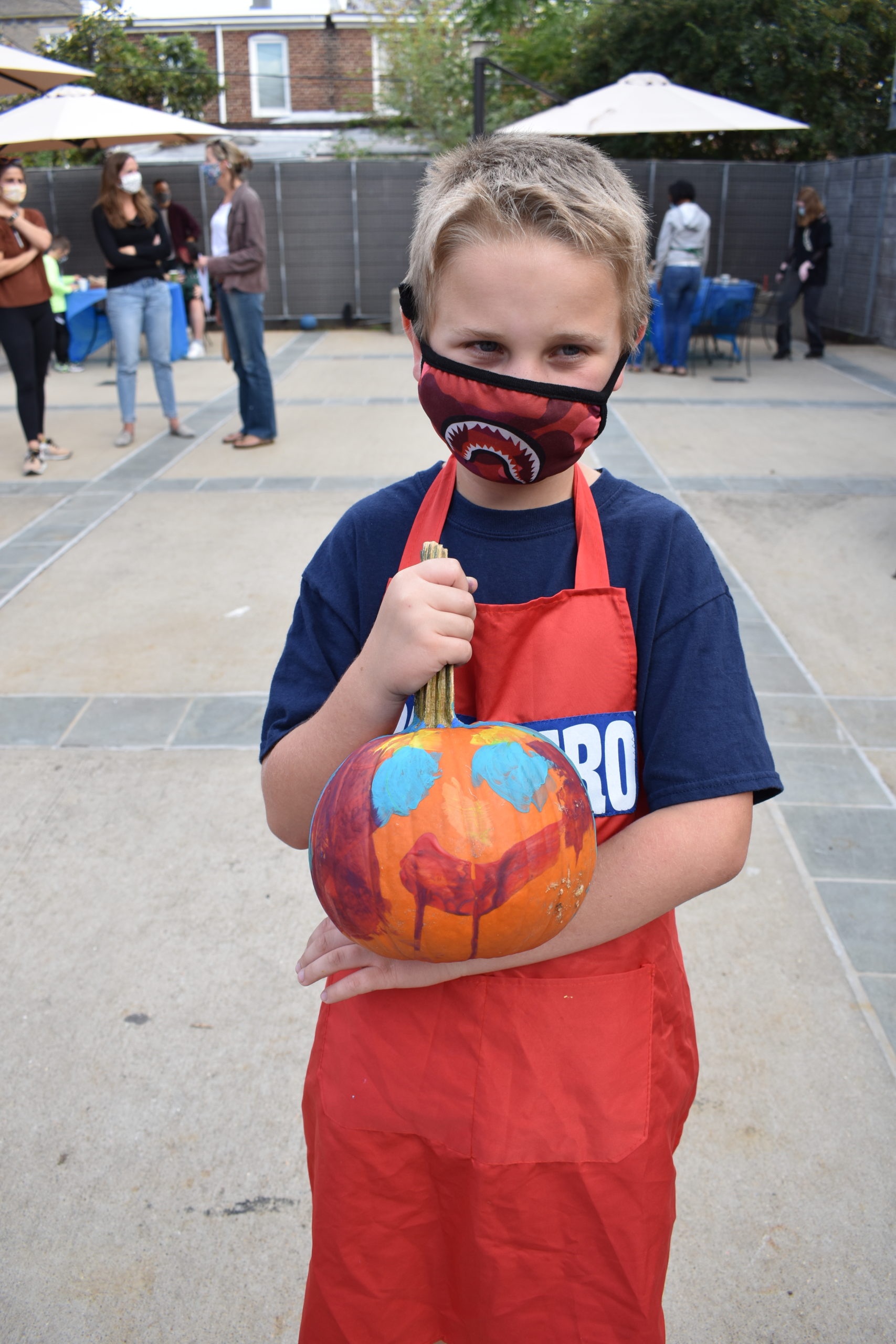 A child holding a pumpkin painted with a face