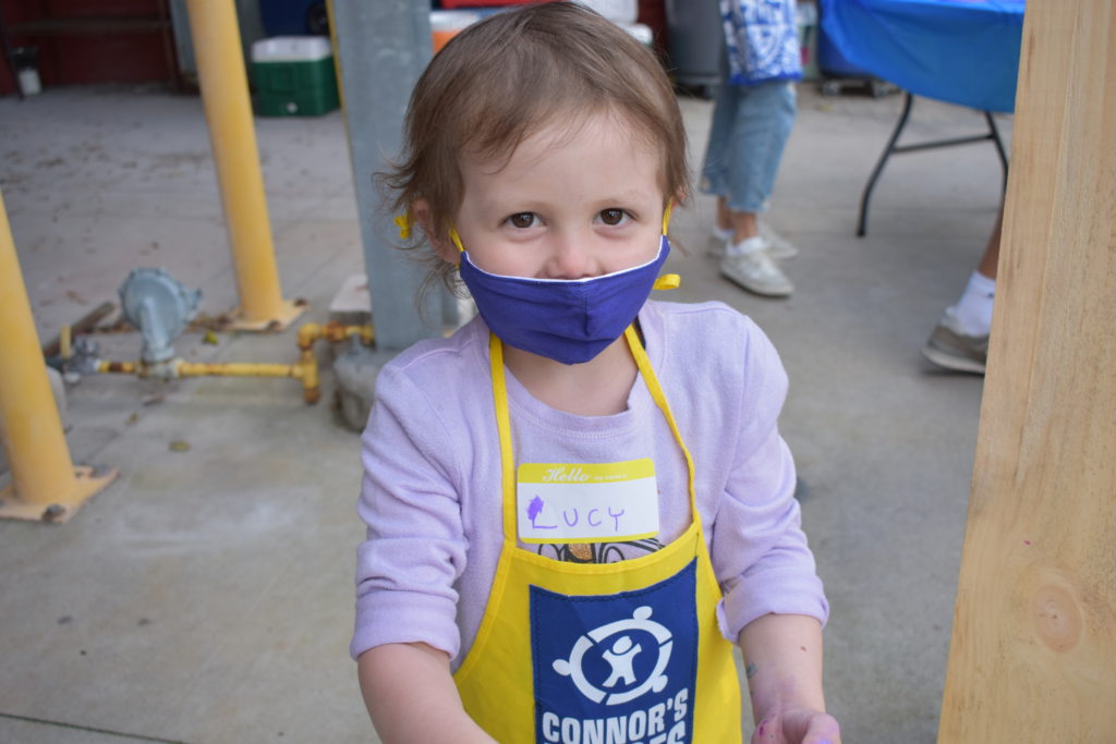 A child wearing a facemask and a yellow apron