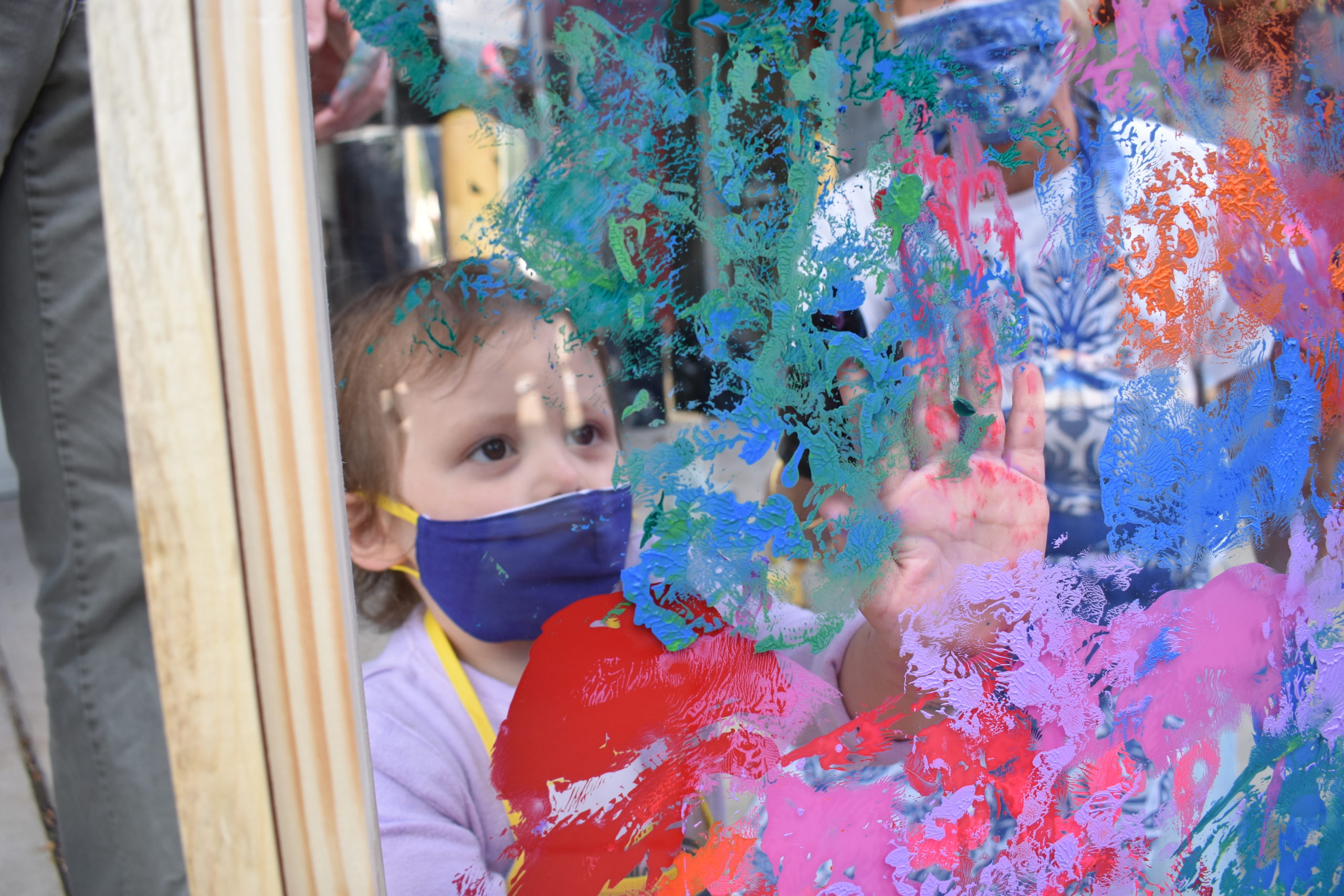 A child touching a piece of clear plastic covered with paint