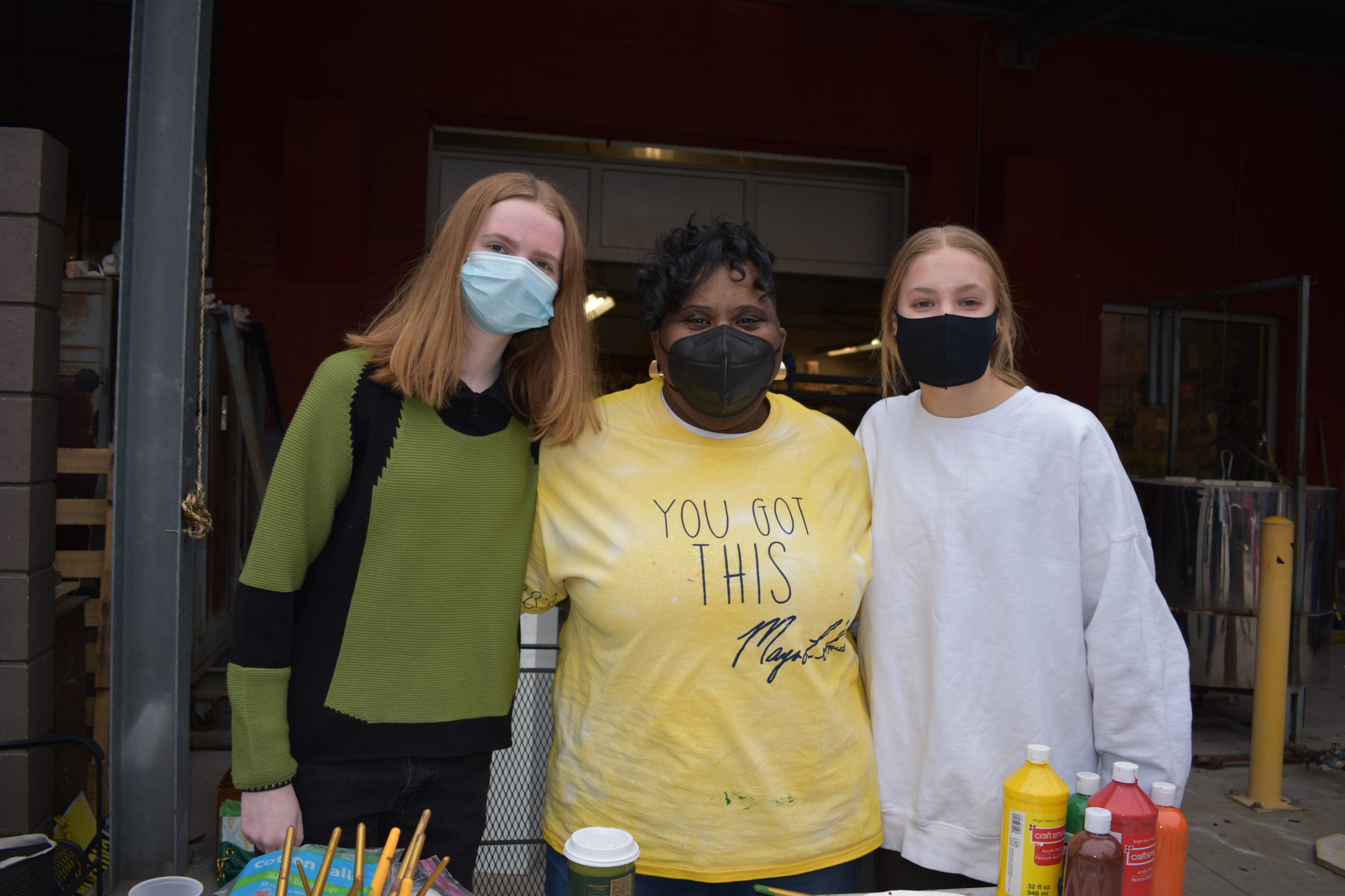 A woman and two teenagers wearing cloth masks and standing together