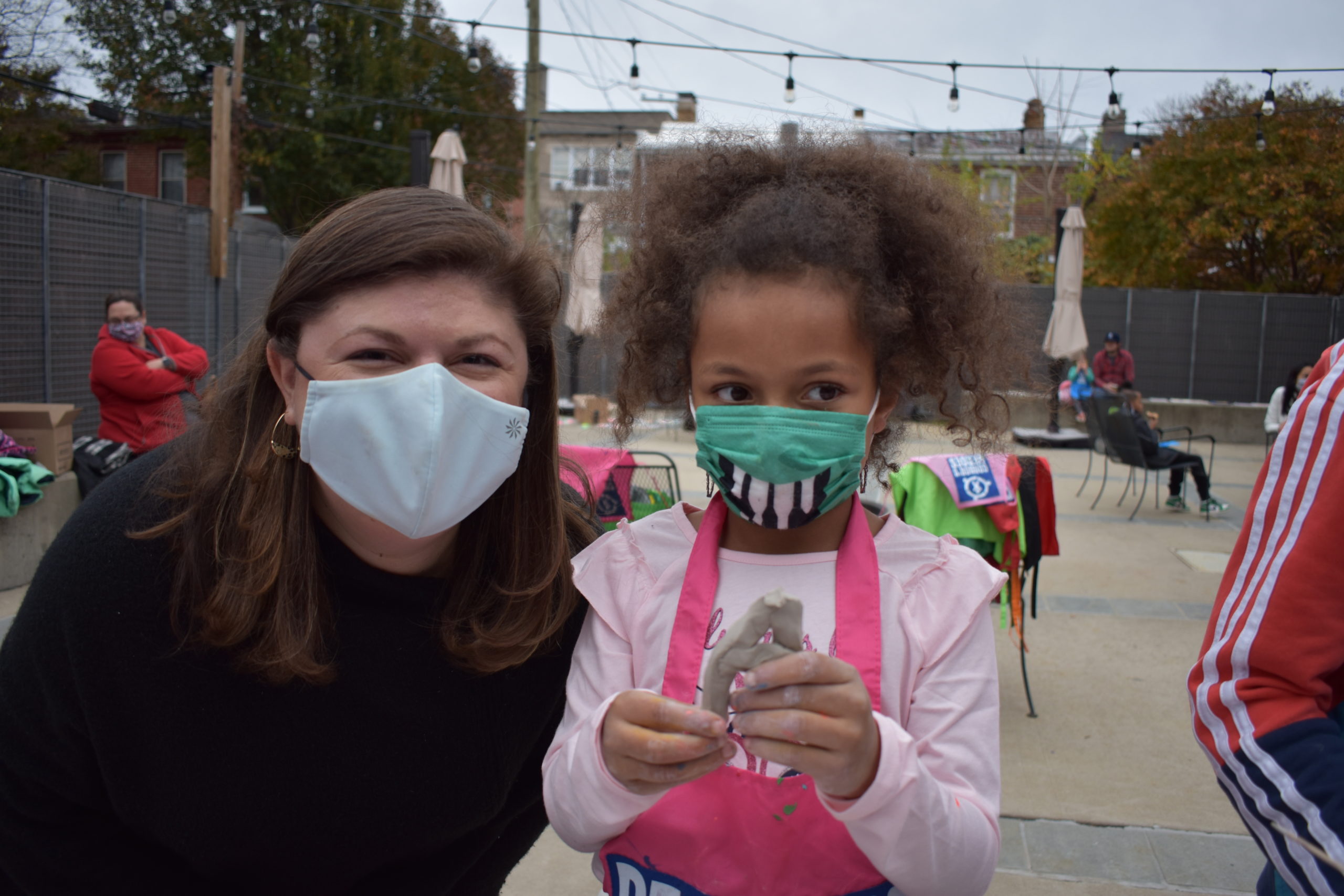 A girl standing next to a woman both are wearing cloth face masks