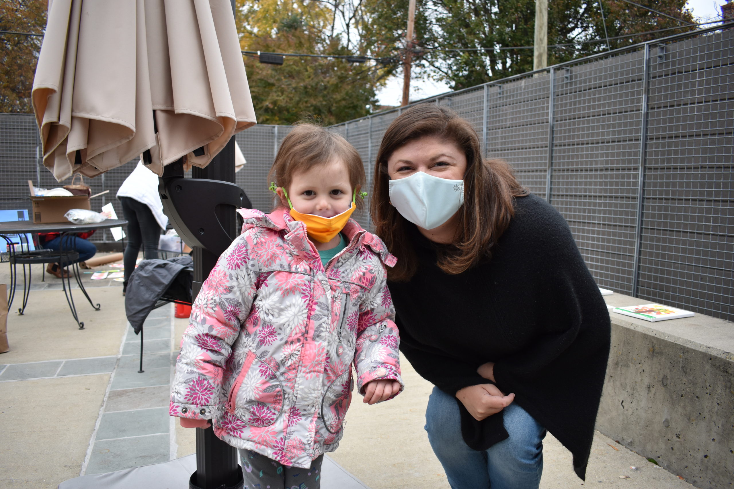 A girl standing next to a woman both are wearing cloth face masks