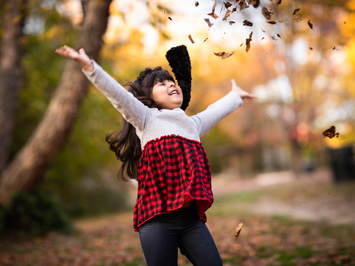 A little girl throwing leaves in the air