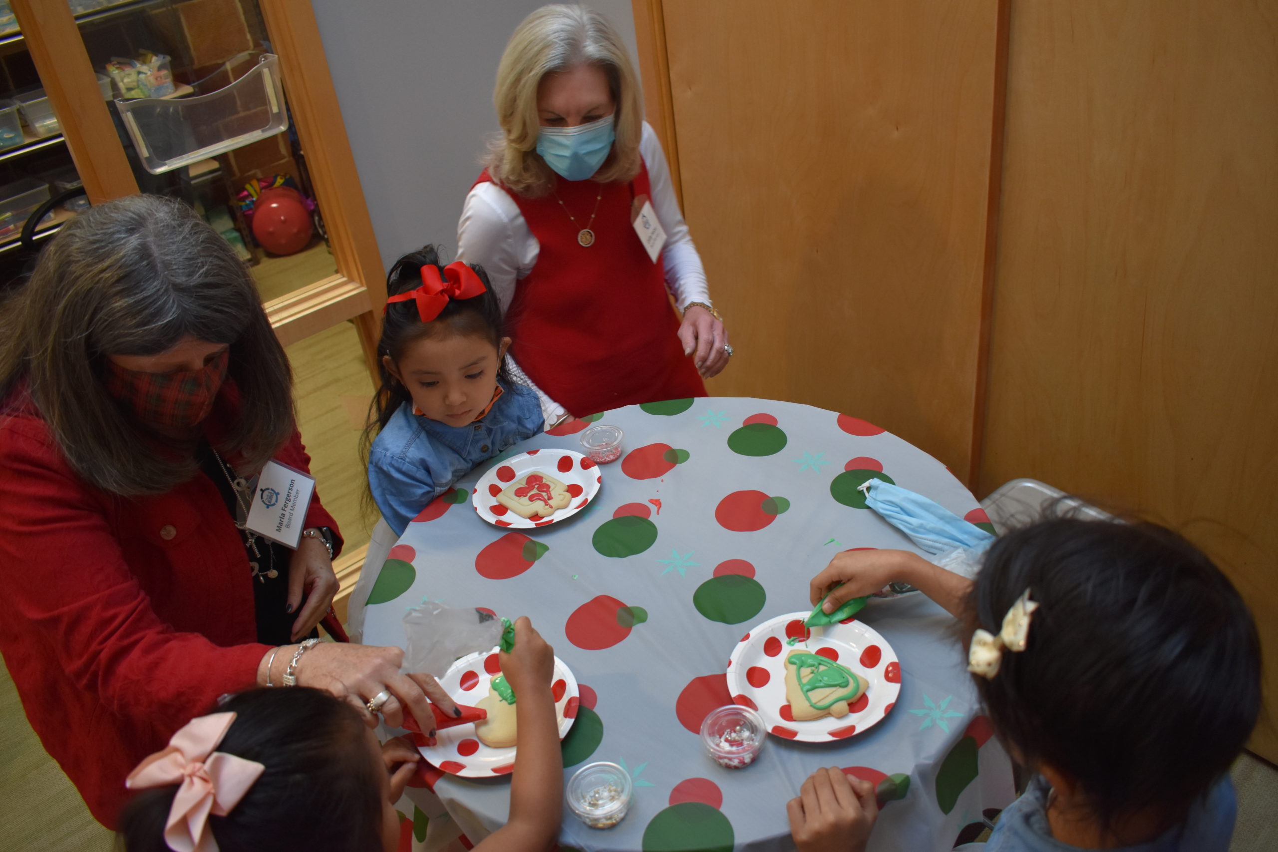 Children are decorating cookies with the help of two adults