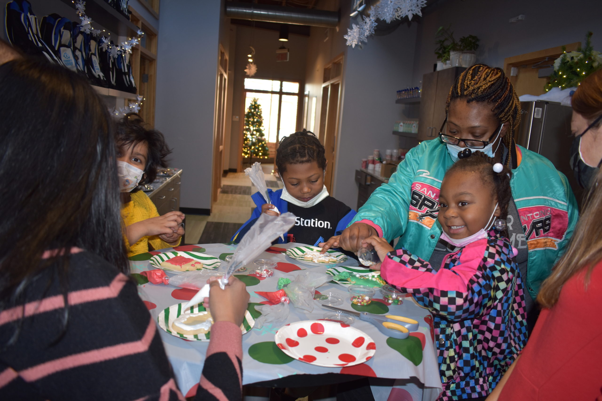 A group of children sitting together at a table decorating cookies with icing