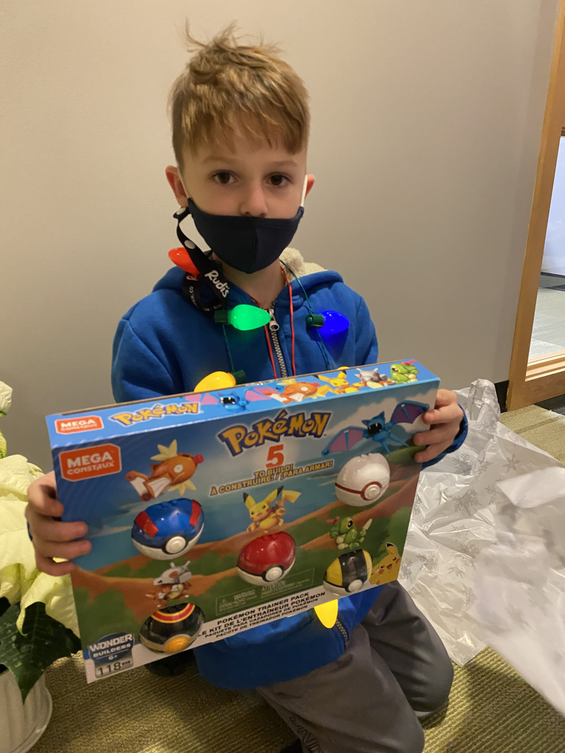 A boy holding up a pokemon set he received as a present