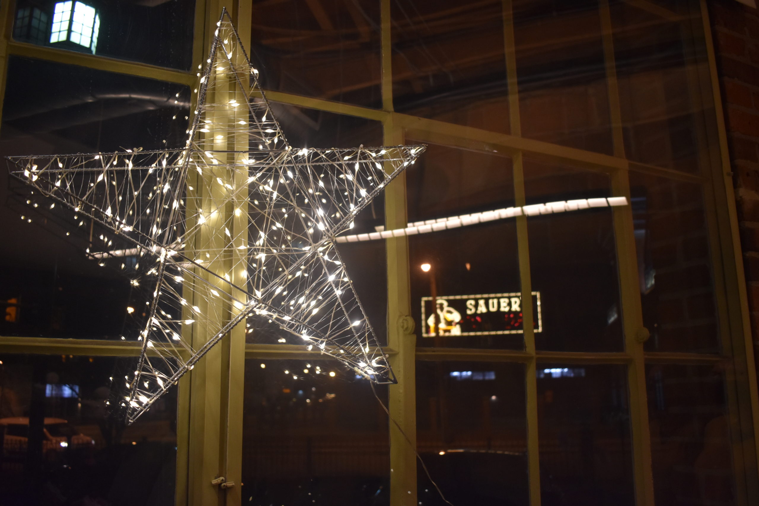 A light-up star in a window with a neon sign behind it