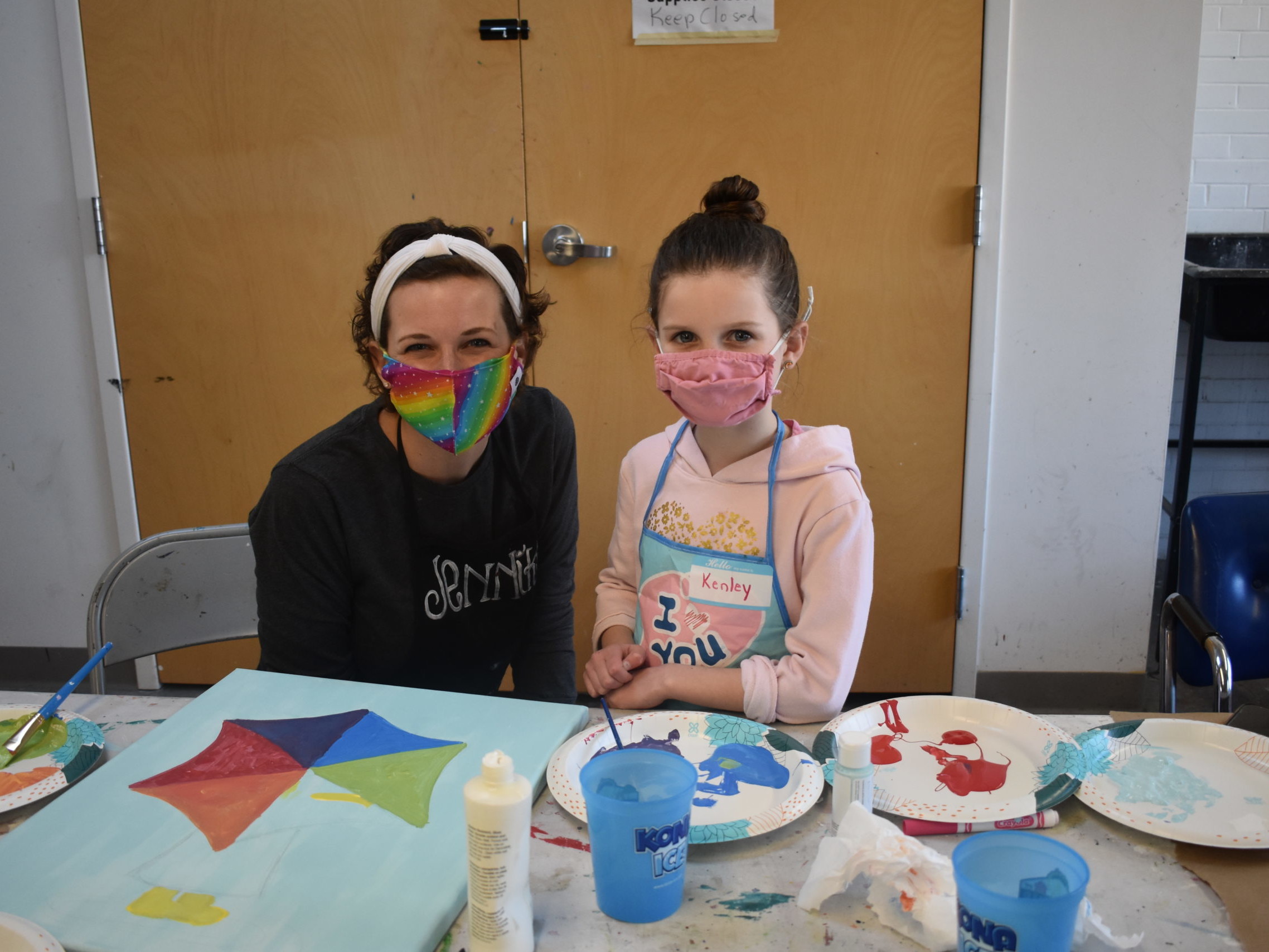 A woman and a child working together on a painting in an art studio