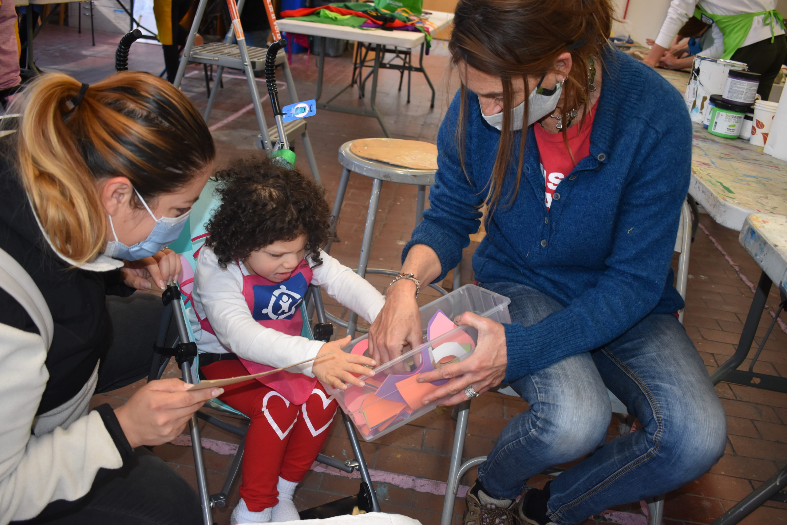 A child and her mother in an art studio working on a craft with a artist