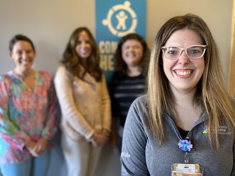 A woman smiling standing in front of three people who are in an office