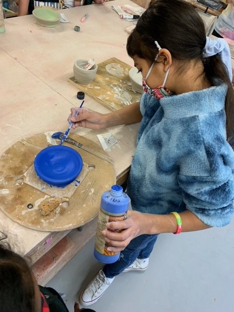 A child painting a clay bowl