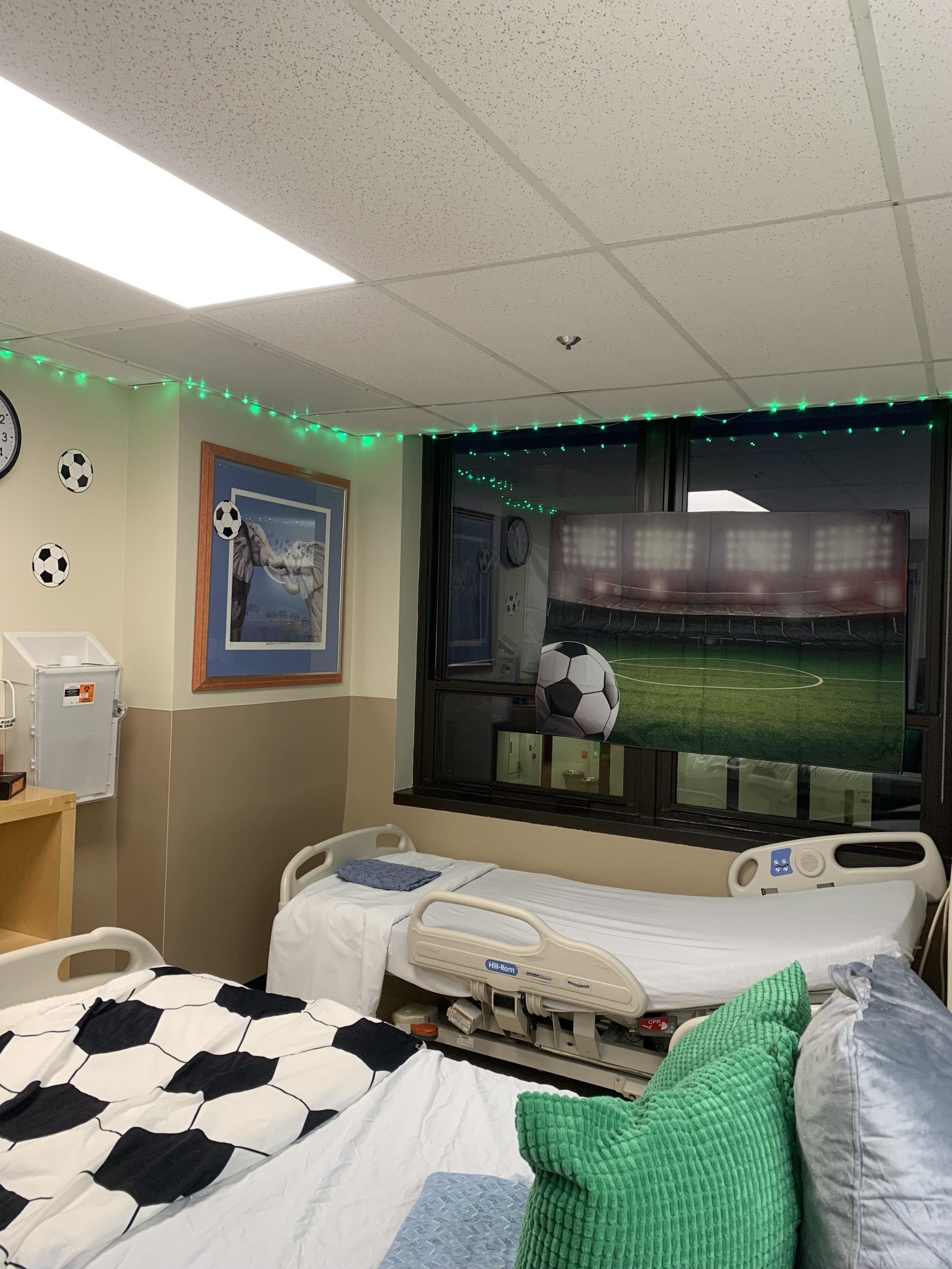 A hospital room with stickers of soccer balls and posters on the wall