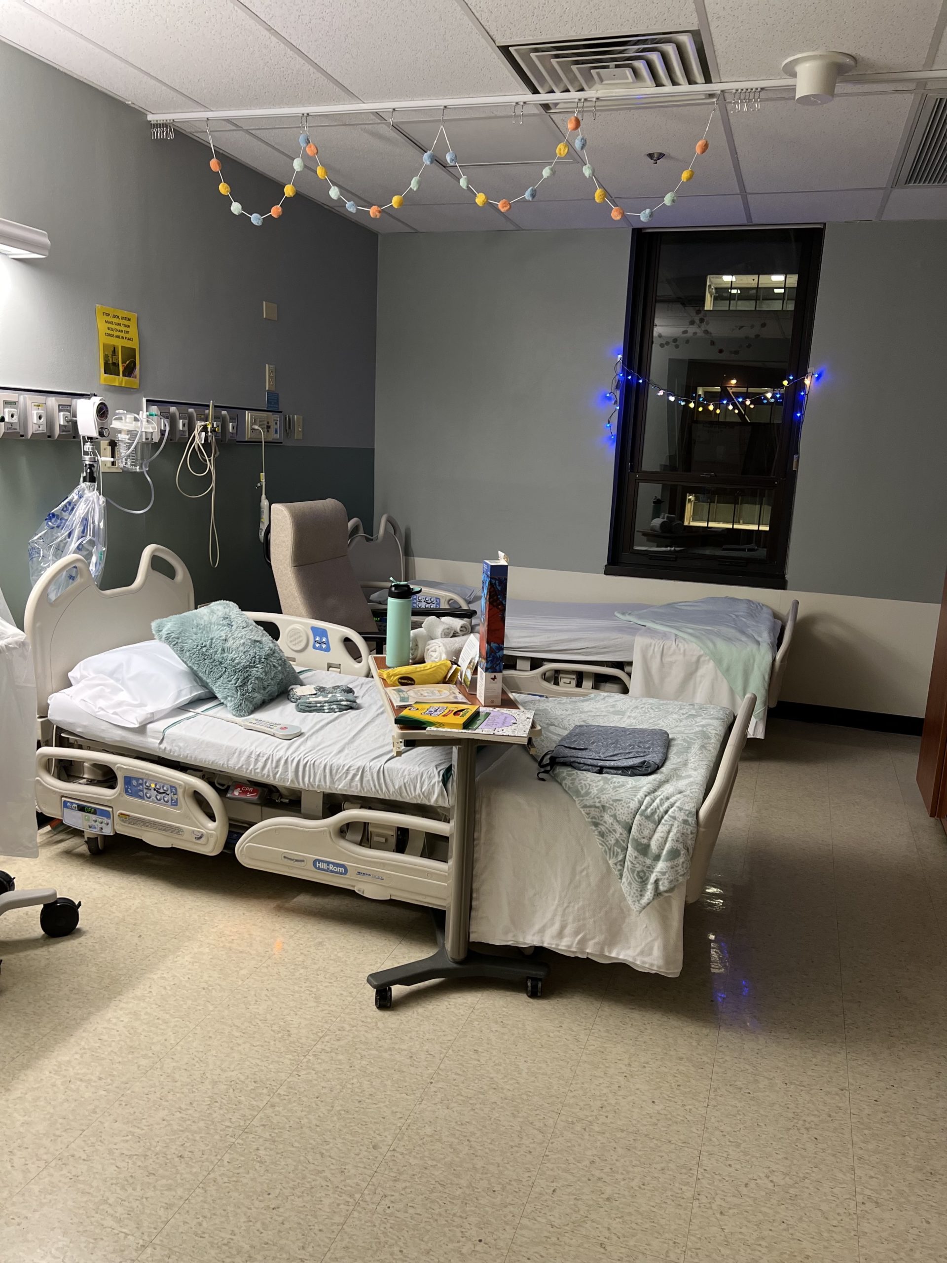 A hospital room decorated with holiday lights