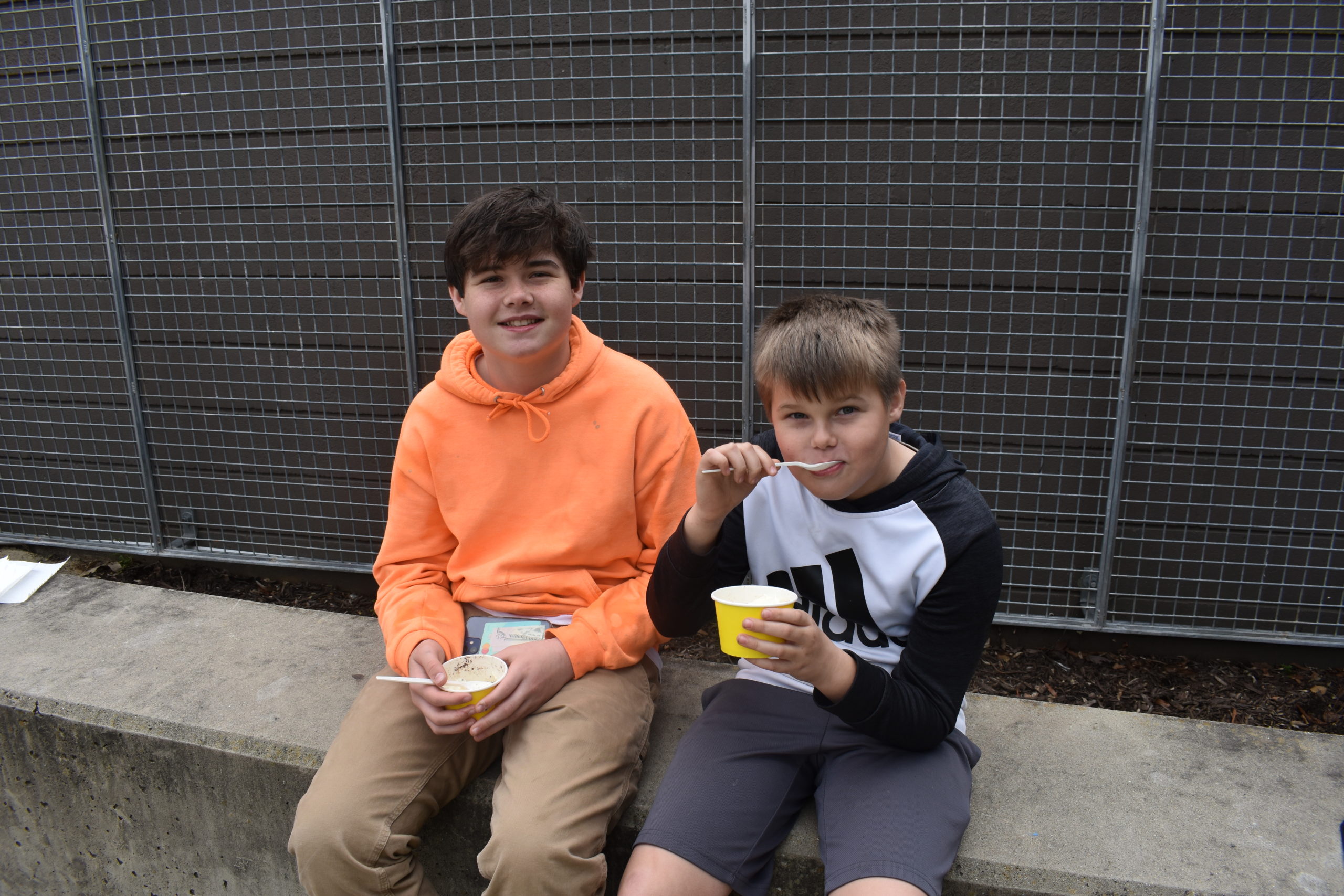 At Connors Heroes Art Session two boys are sitting outdoors eating ice cream
