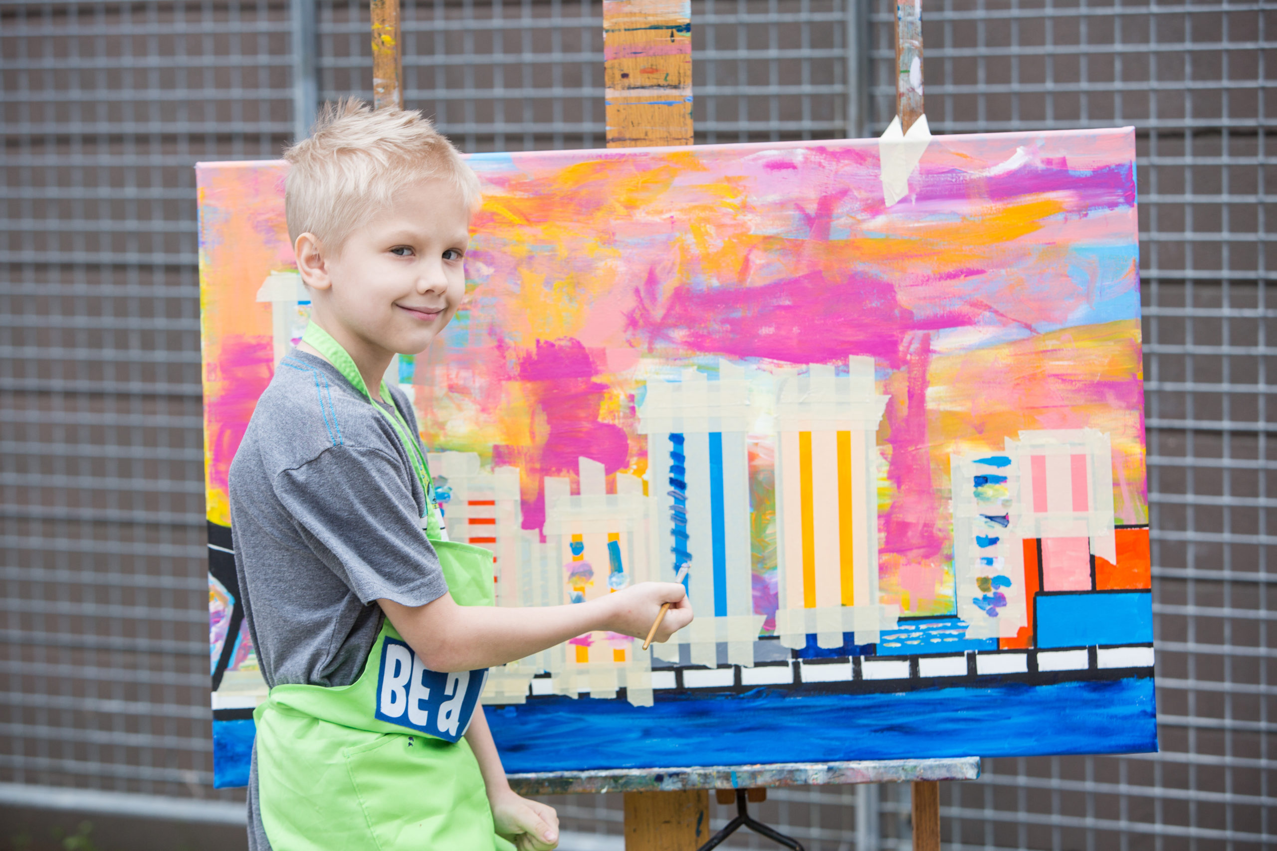A boy painting a picture of a city skyline