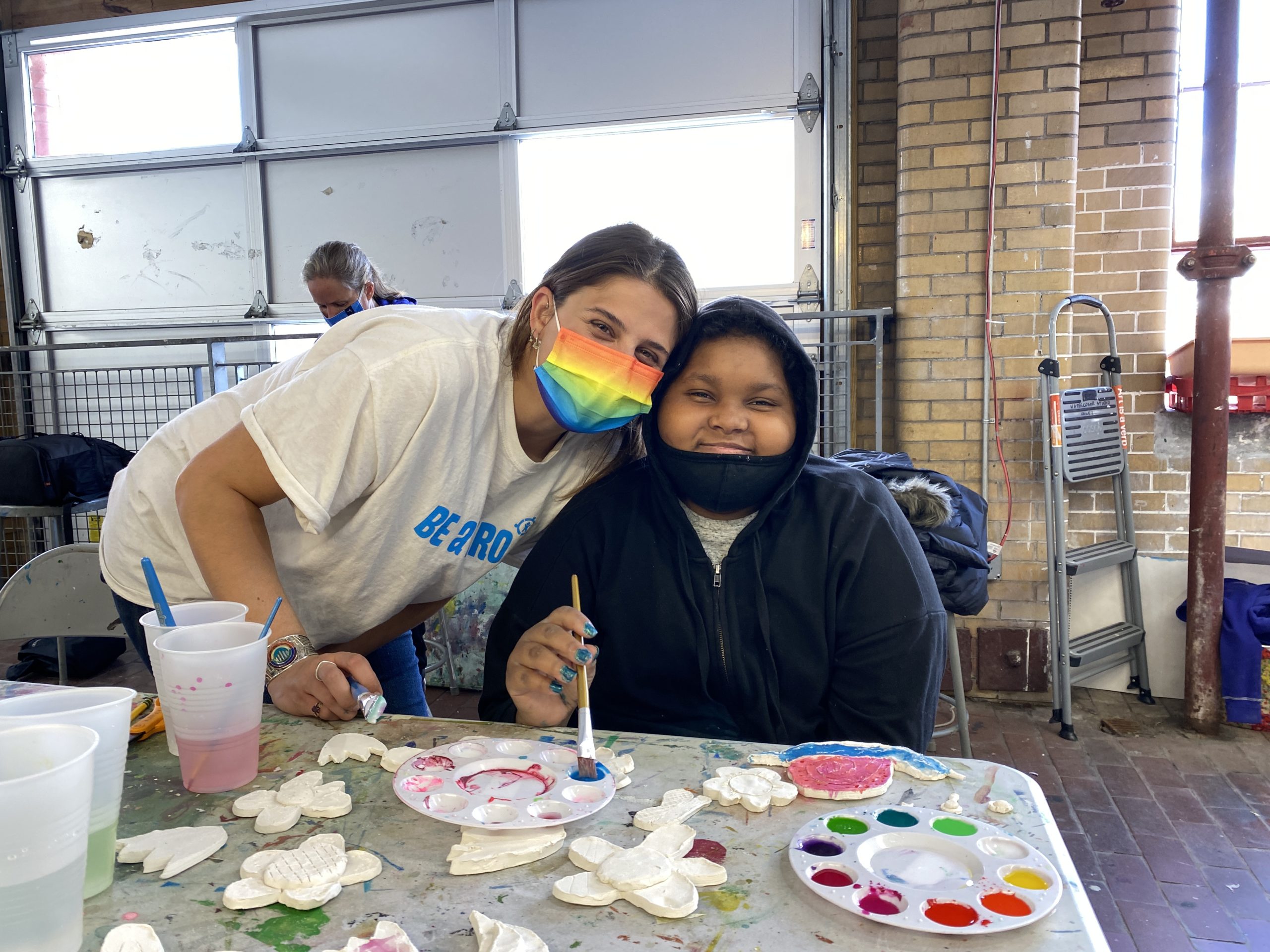 A woman and a teen are in an art studio working on a painting together