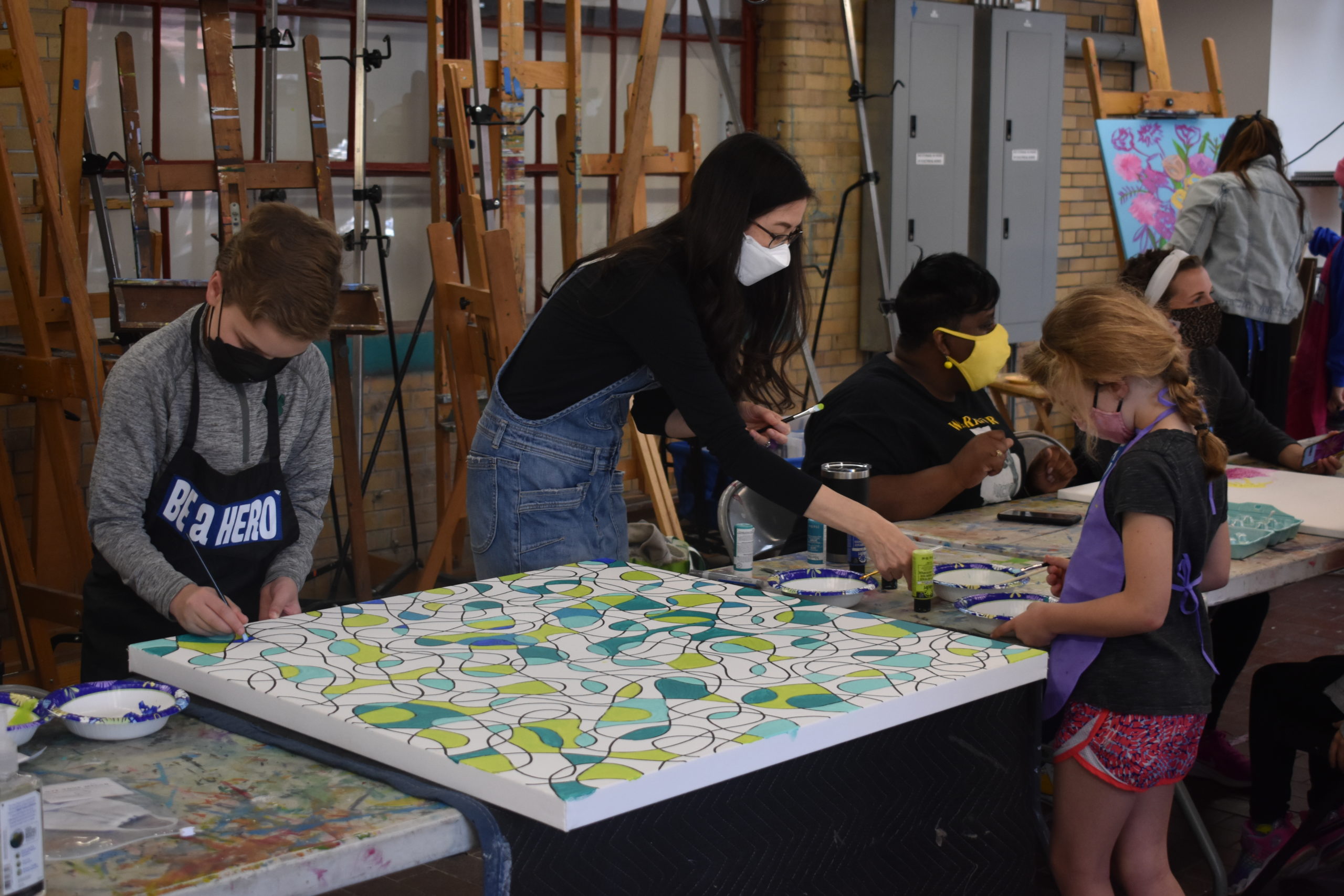 An art studio with kids and adults working on different paintings