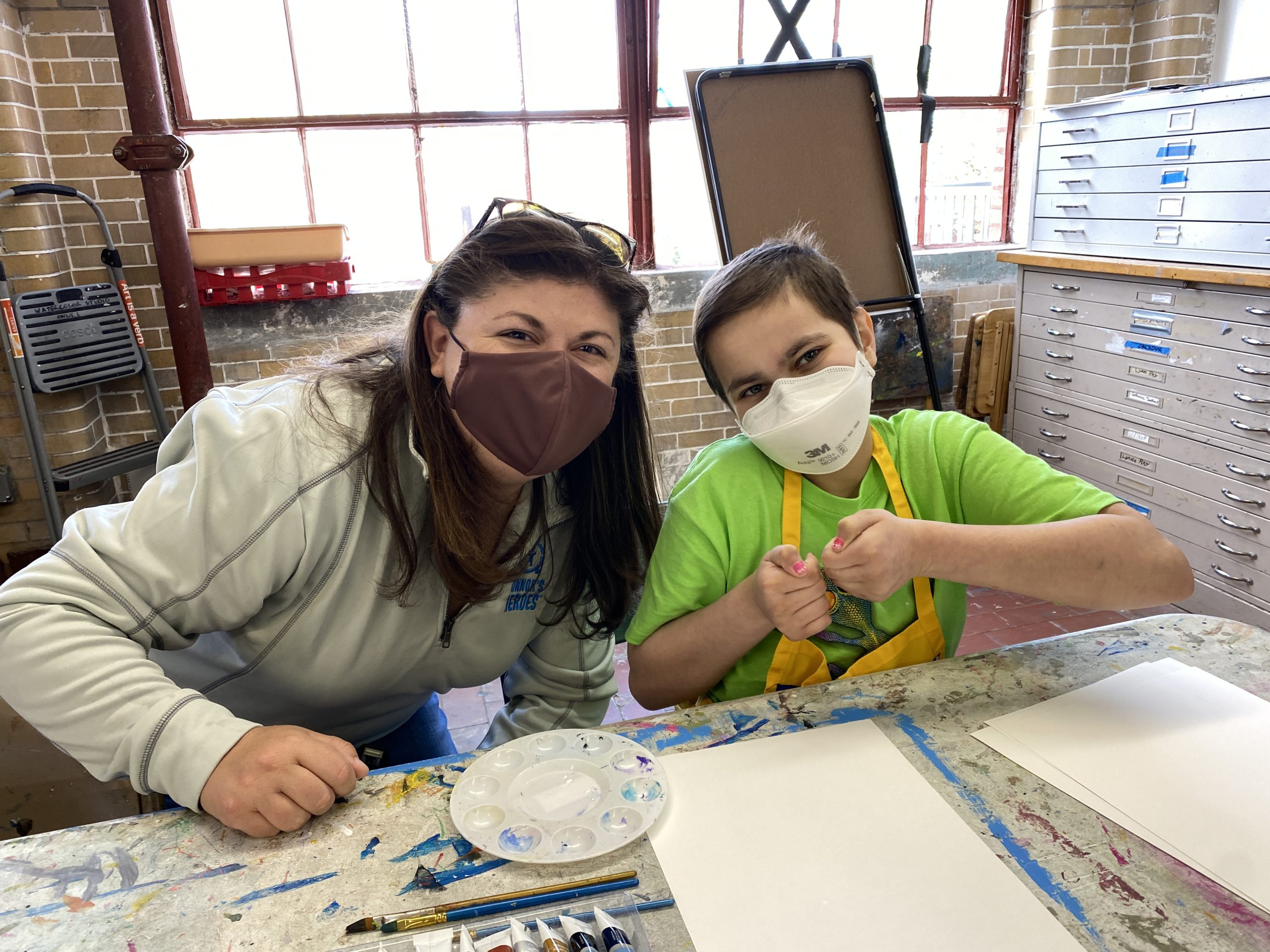 A woman is sitting next to a girl in an art studio