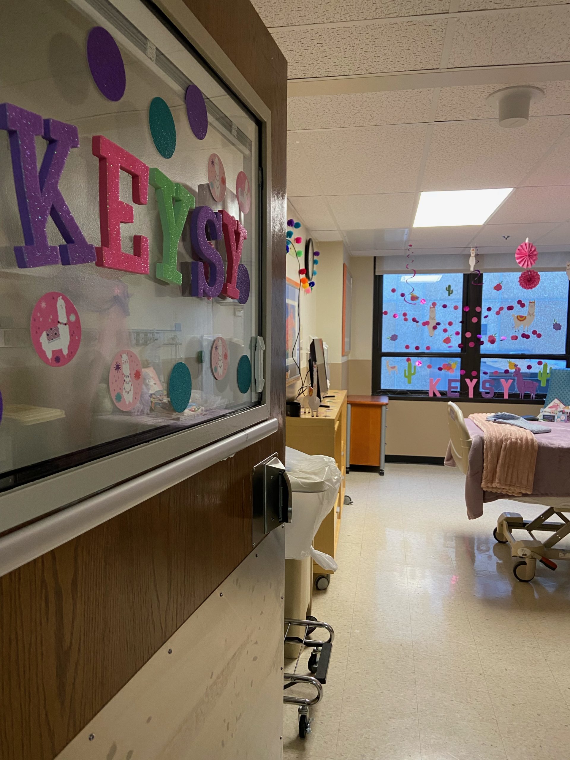 the door to a hospital room is open inside the room is decorated with pink wall hangings