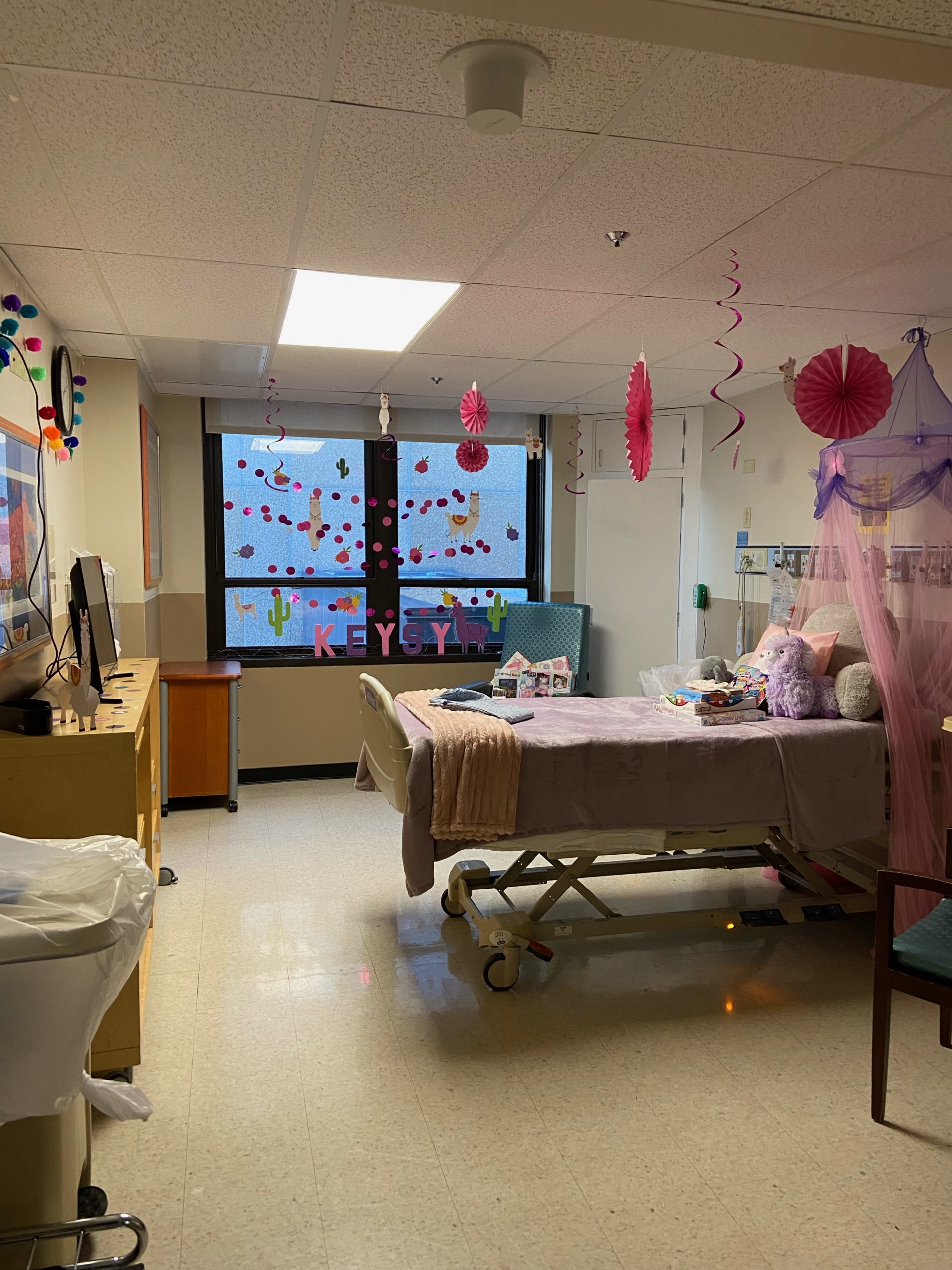 a hospital room decorated with pink wall hangings and bedding