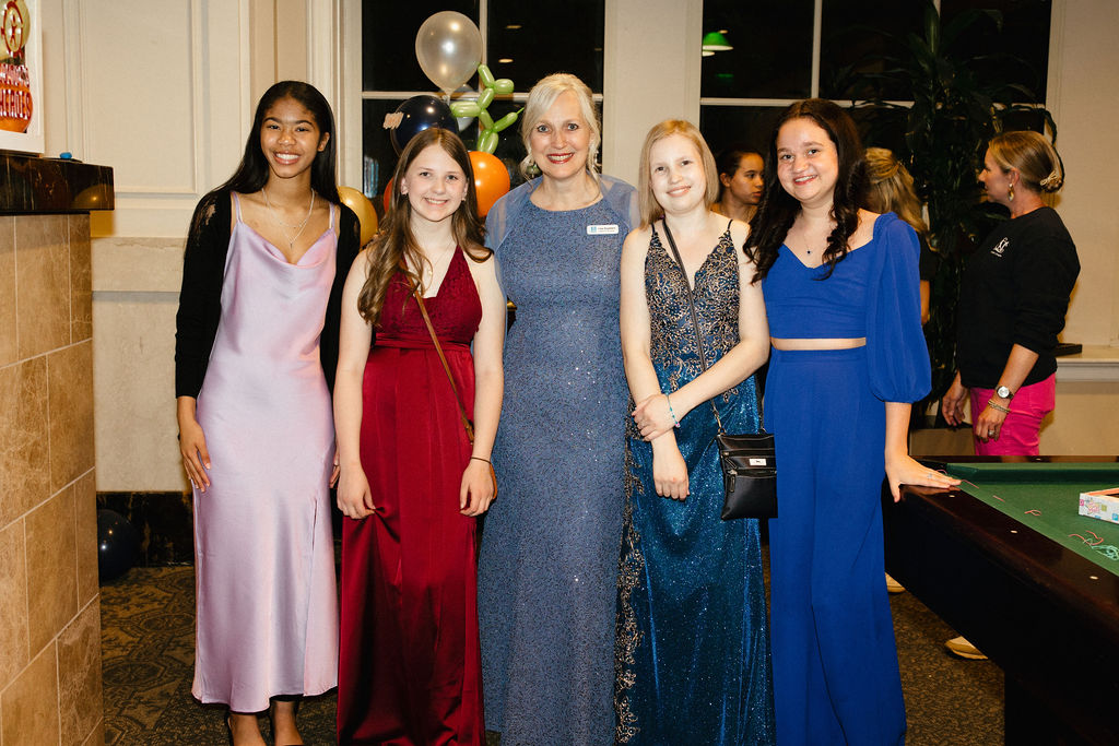 A woman standing with four teenagers Everyone is dressed up for a gala