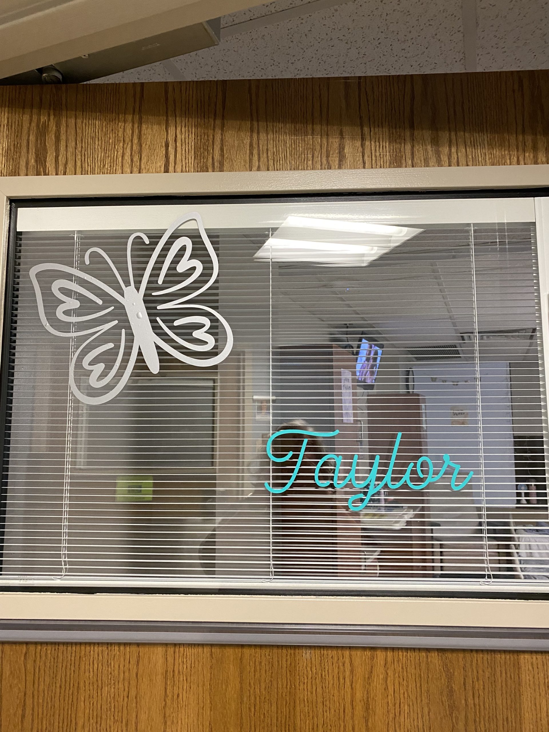 A window decorated with a sticker of a butterfly and the name taylor