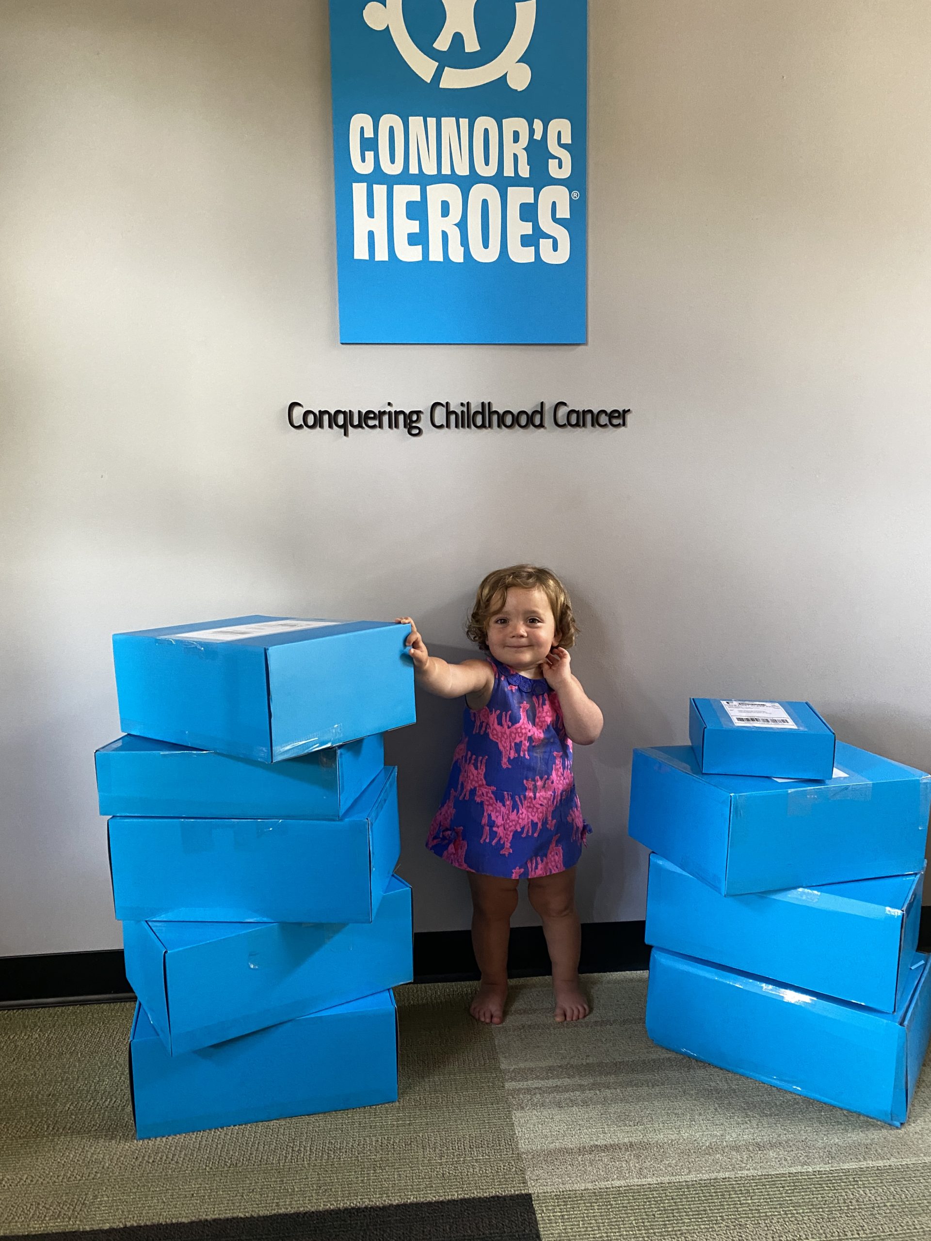 A toddler standing between two piles of blue boxes