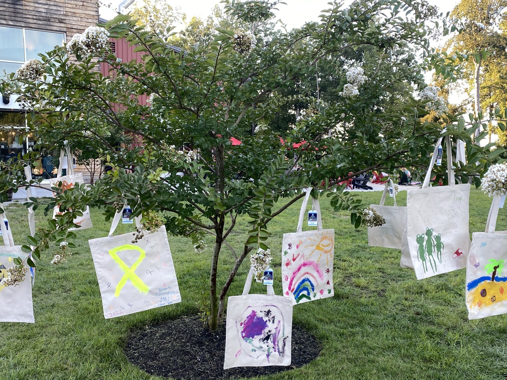 Tote bags are hanging from a tree