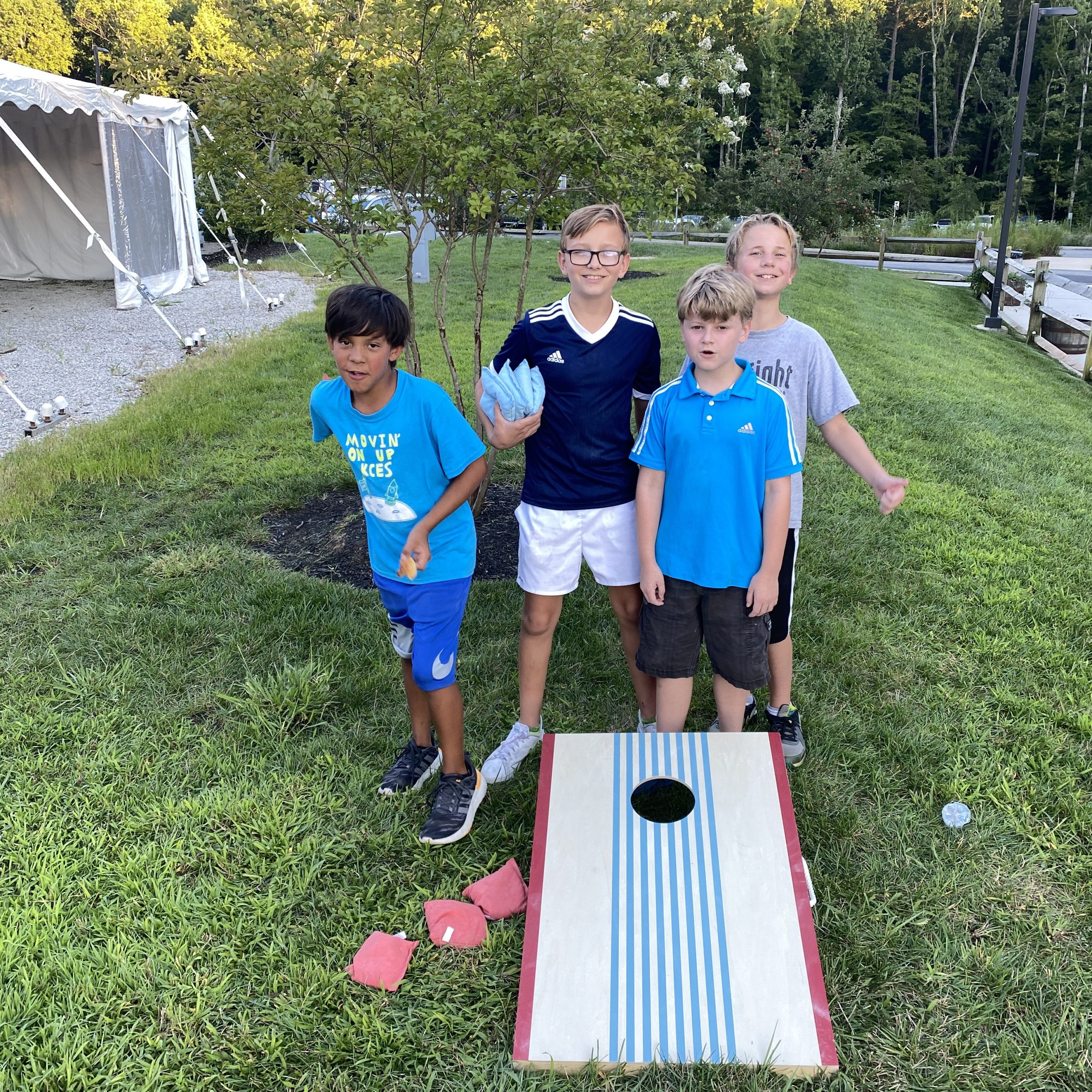 Four boys are playing the game corn hole