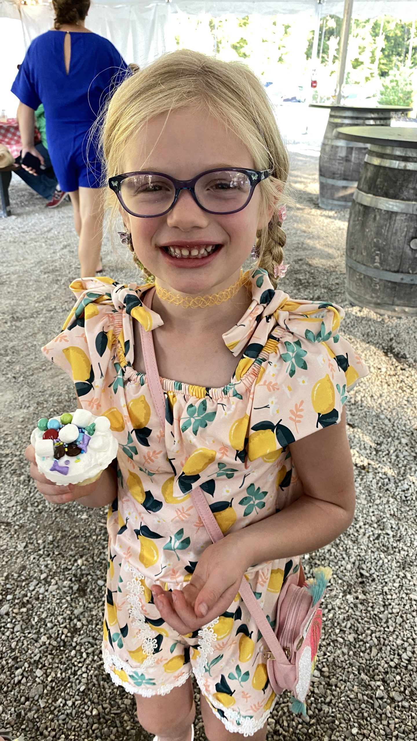 A girl is smiling and holding a cupcake she decorated with marshamallows