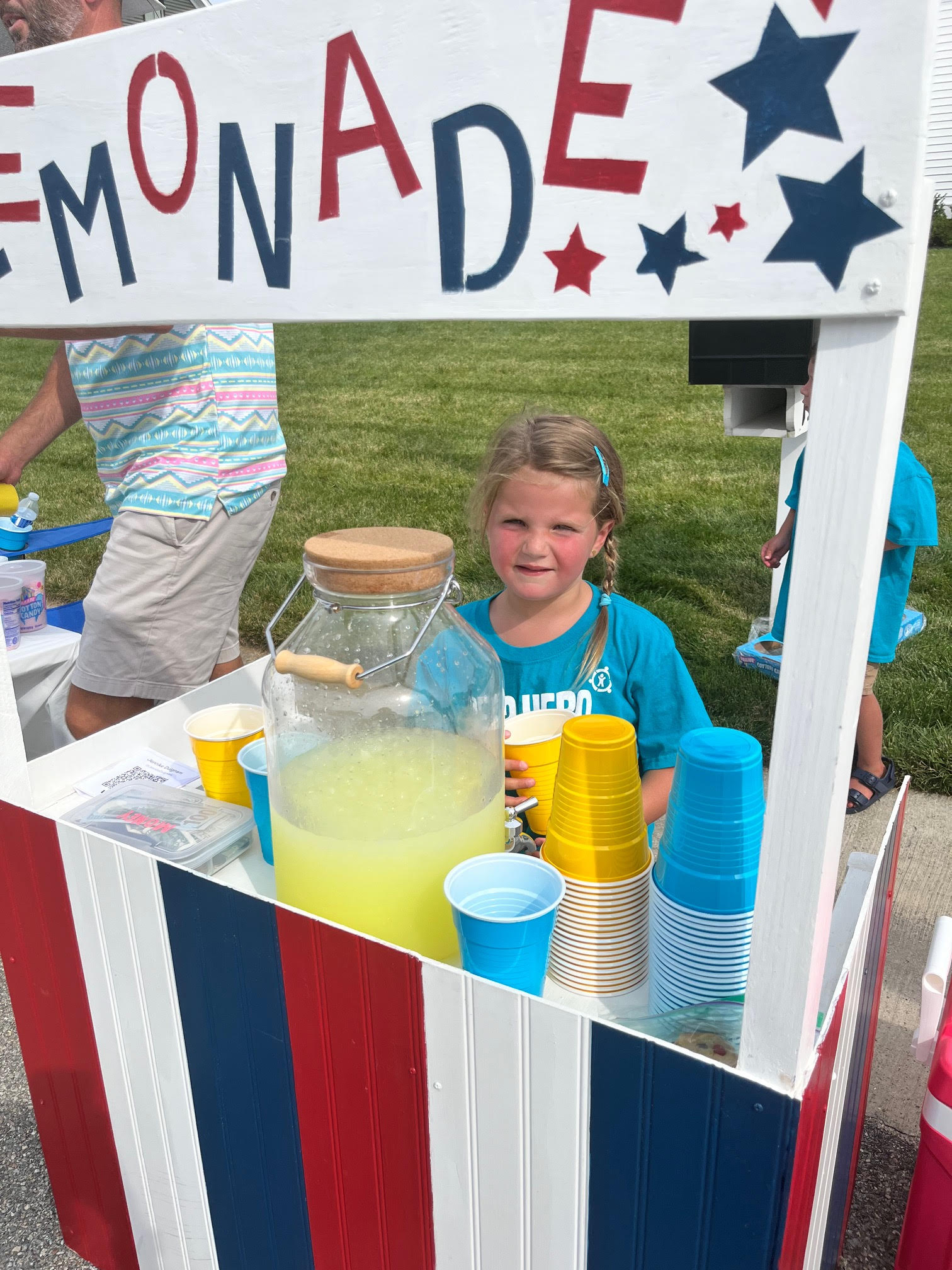 Girl sitting behind a lemonade stand