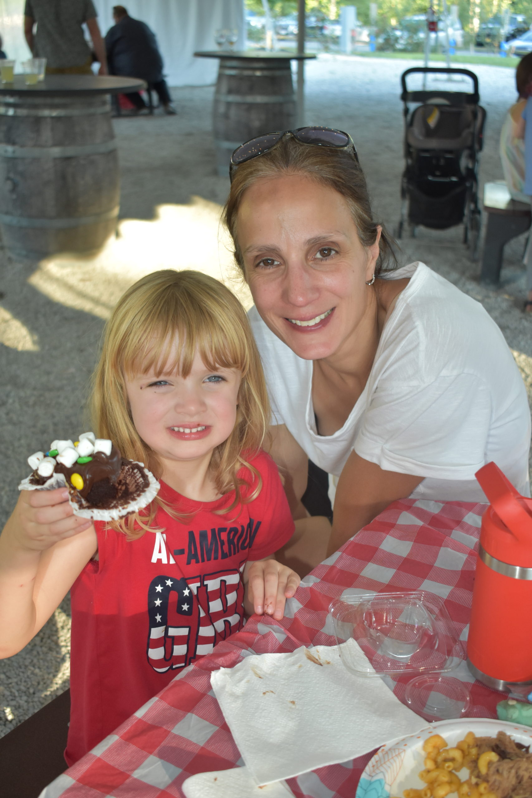 Girl holding up a chocolate cupcake She is sitting with her mom