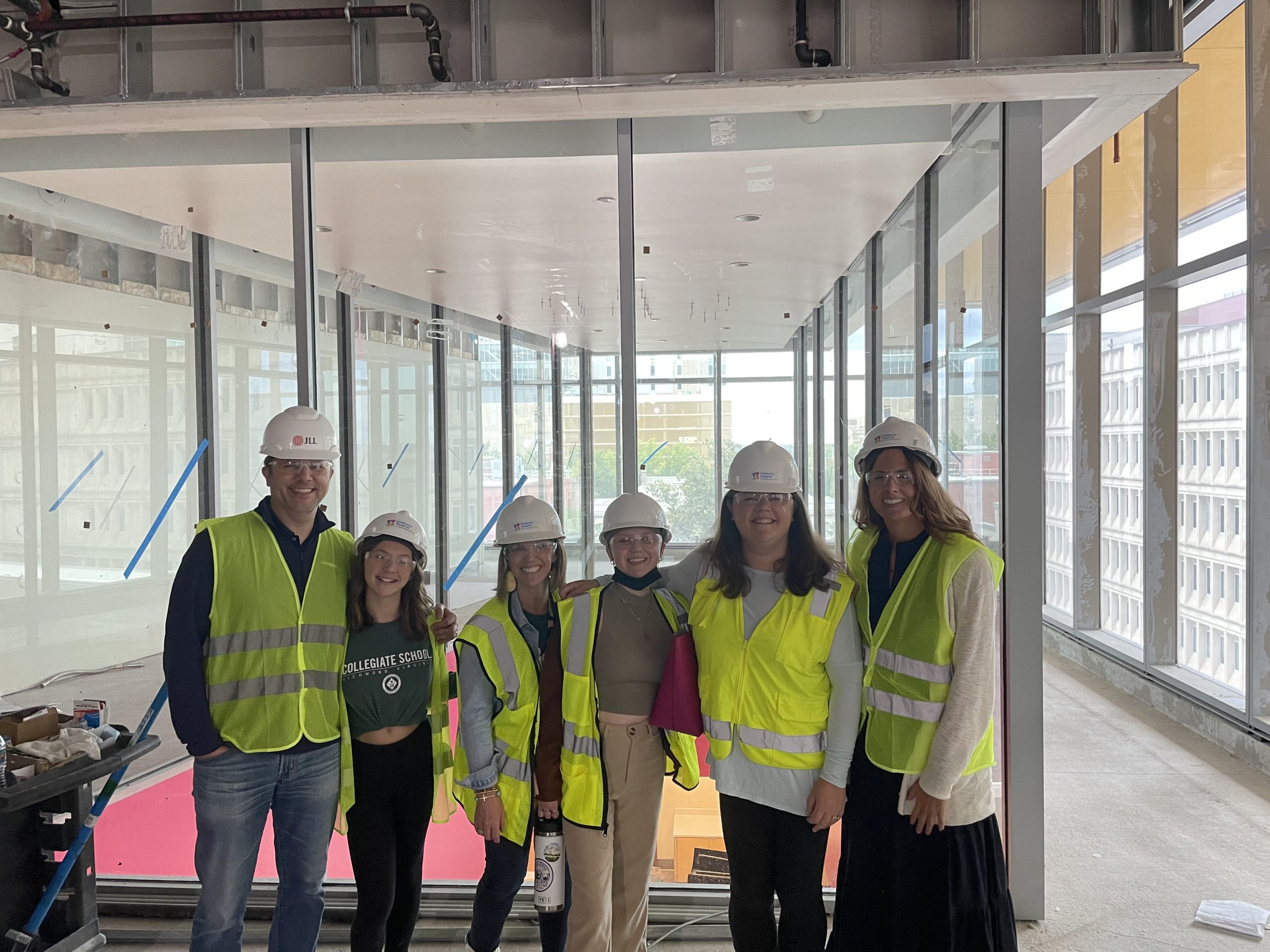 6 people standing inside a construction site wearing hardhats