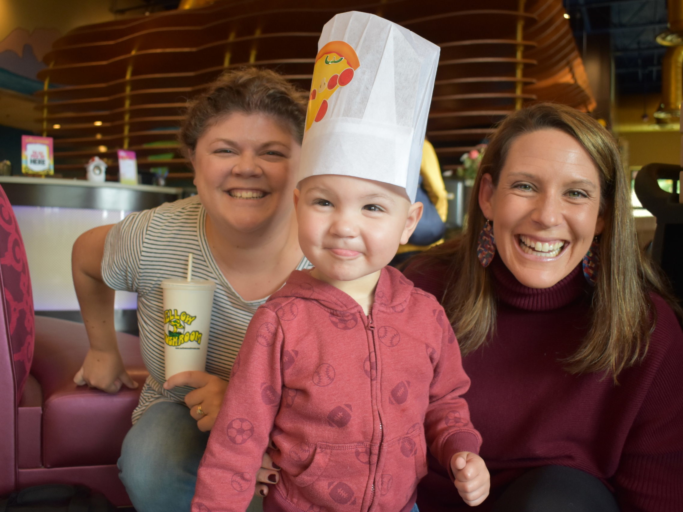 A toddler stands with two women