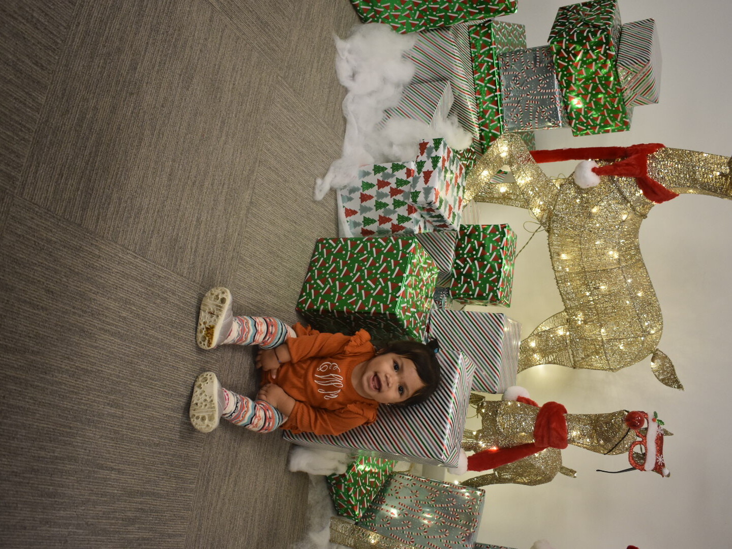 A baby sits in front of a holiday display