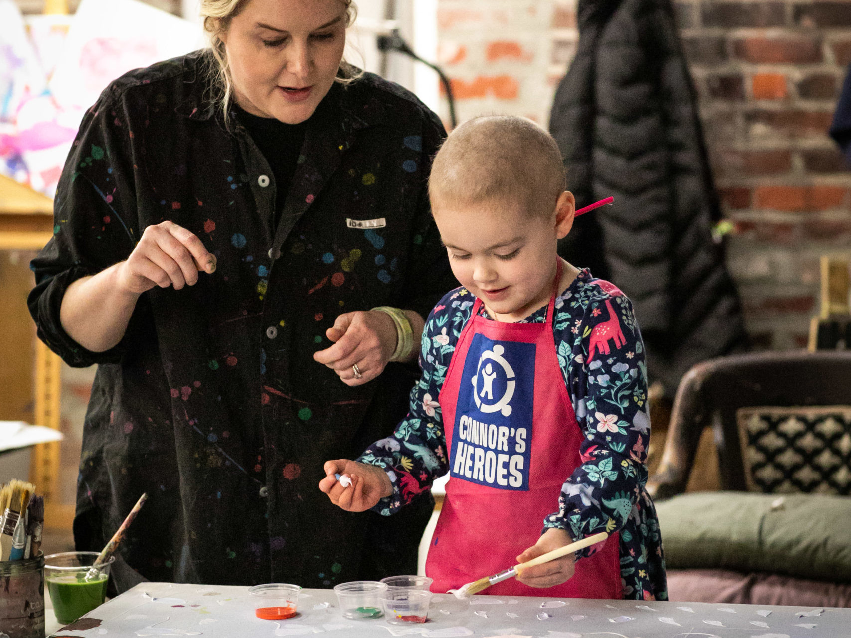 Artist helps a girl paint on the canvas