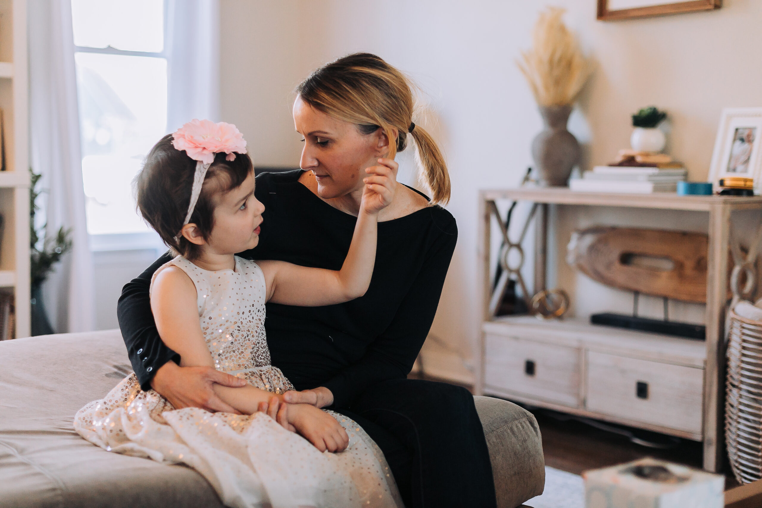 Ava wearing a glittery dress sitting with her mom on her bed