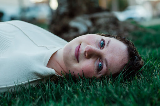 A girl with bright blue eyes is laying in the grass