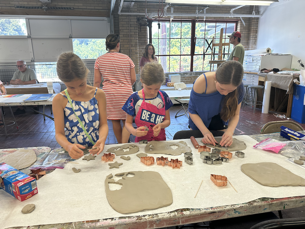 Three girls are sculpting shapes out of clay