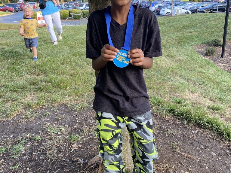 Boy smiling holding up a medal he won