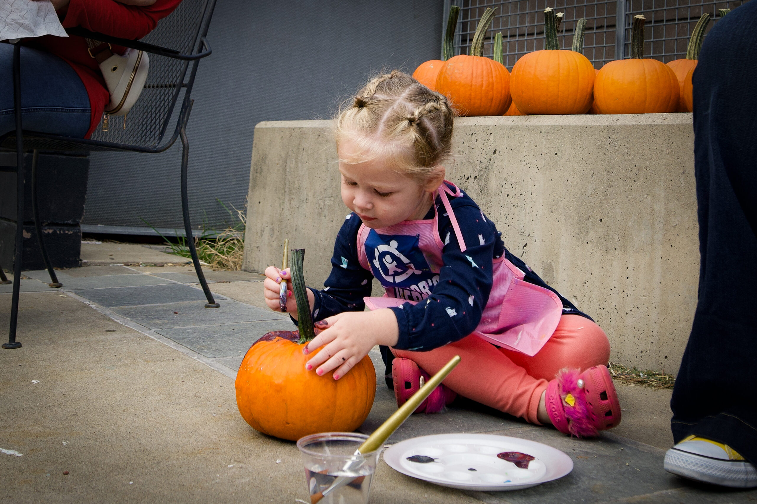 A girl is painting a pumpkin purple